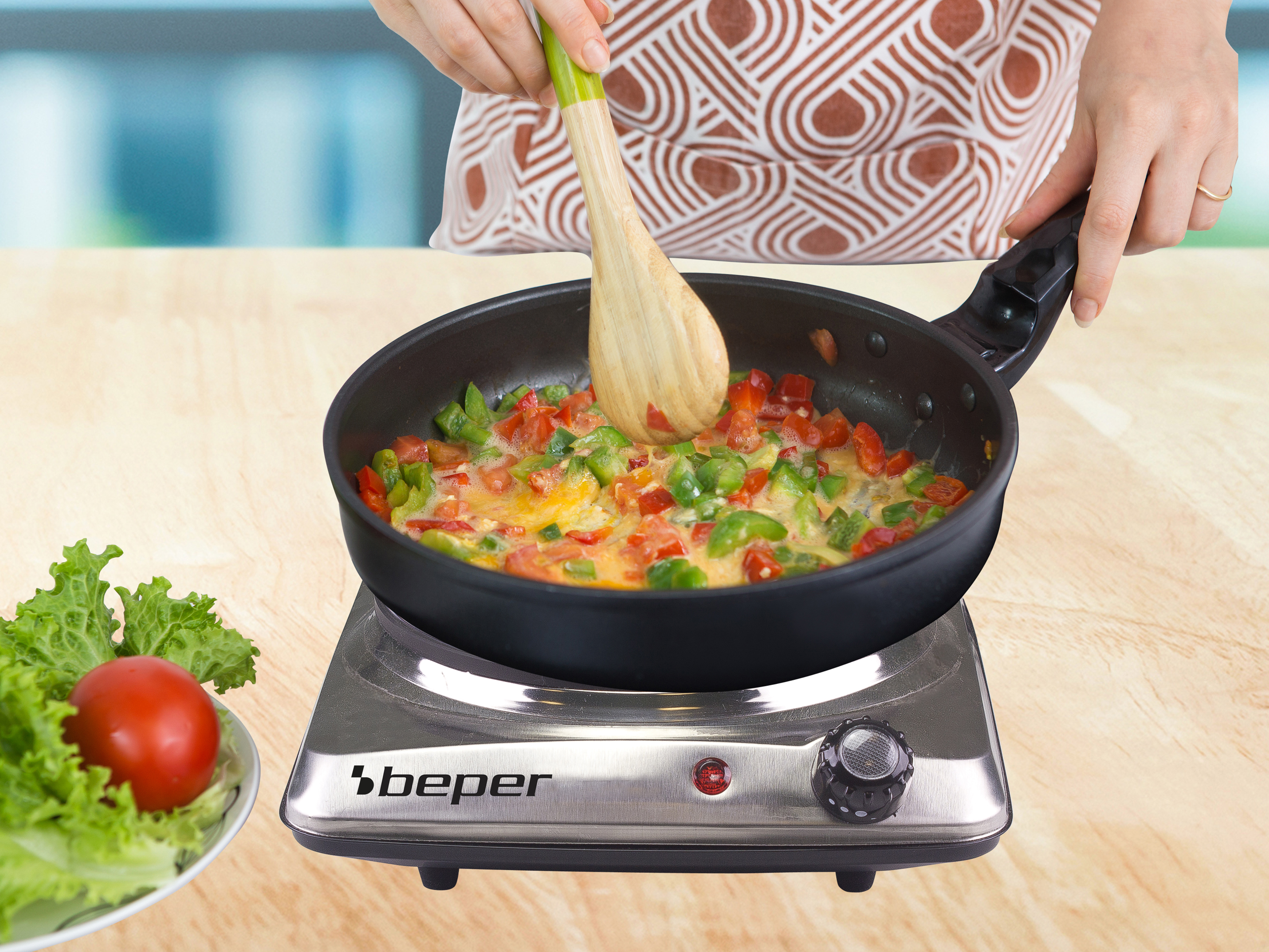 Una persona cucina uova con verdure in una padella su un fornello, con pomodori e lattuga sul lato.