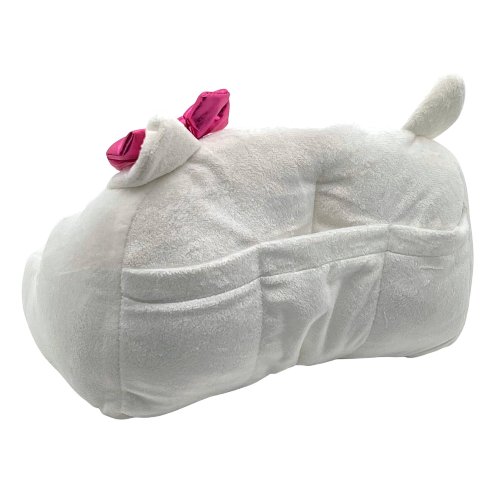 Un peluche blanco con un lazo rosa y tres bolsillos. Tiene forma de oreja.