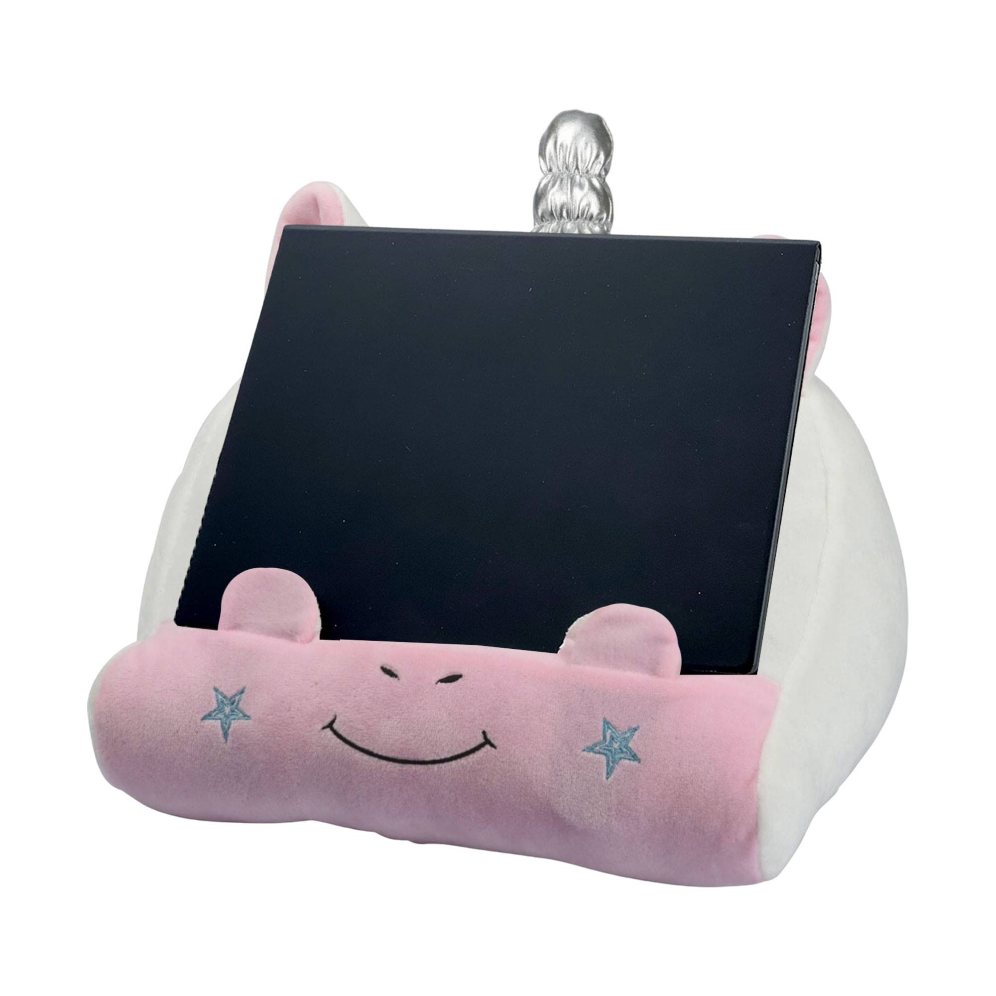 Un soporte para tableta de unicornio rosa con una tableta negra. Tiene una cara sonriente, estrellas y un cuerno plateado.