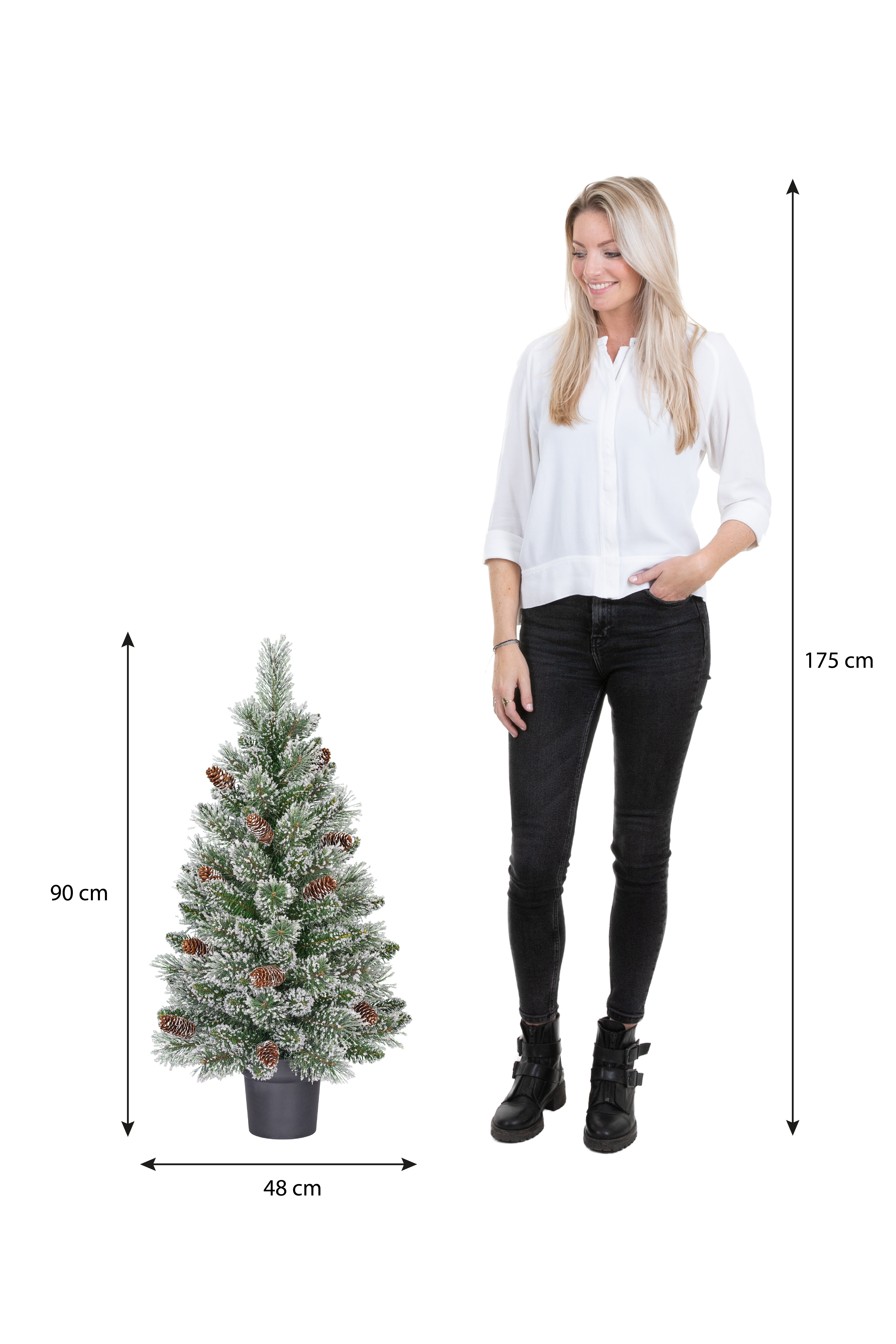 Une femme se tient à côté d'un sapin de Noël enneigé. Des mesures sont fournies. Le fond est blanc.