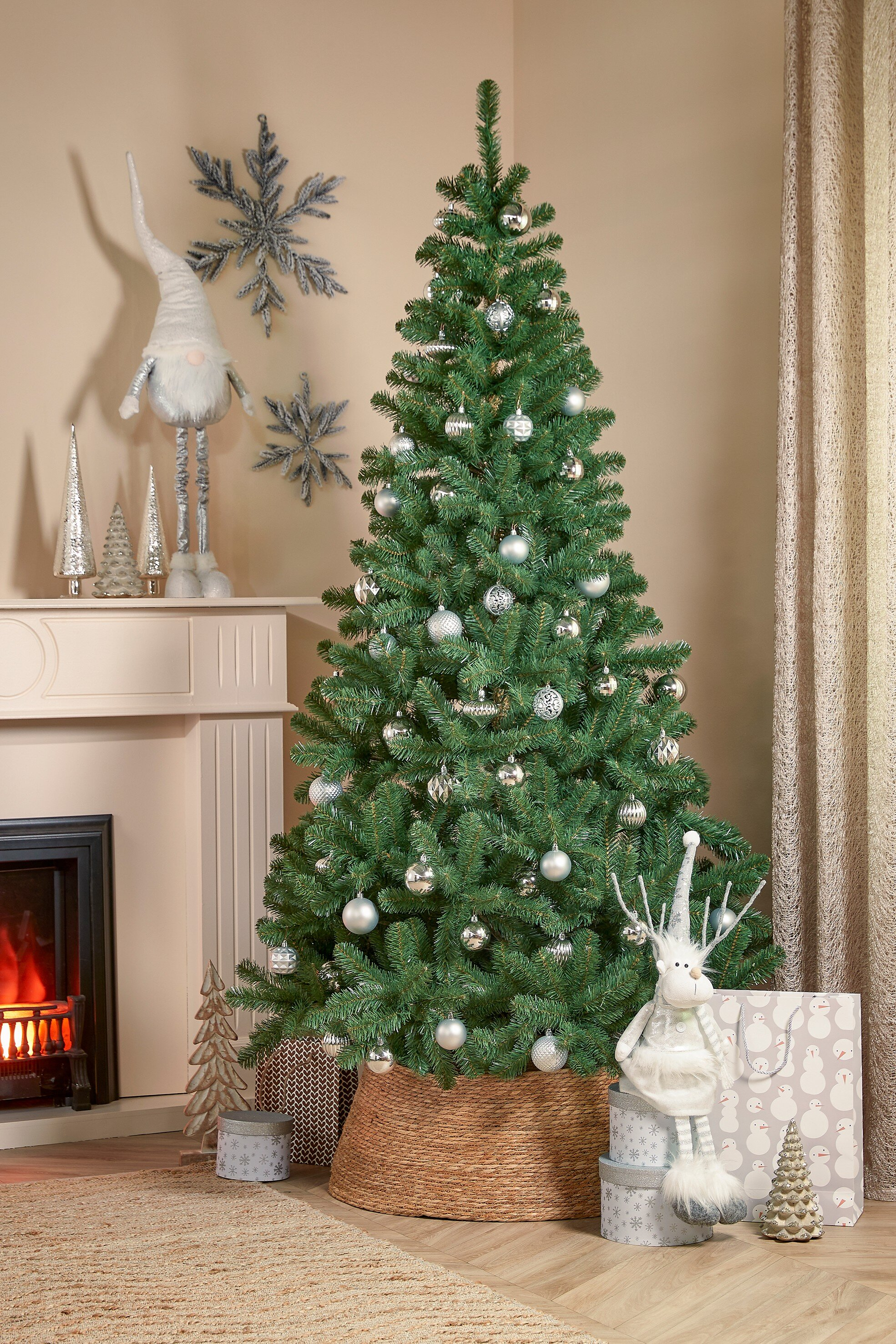 Un sapin de Noël décoré se dresse près d'une cheminée, orné de décorations. Des décorations festives et un éclairage doux créent.