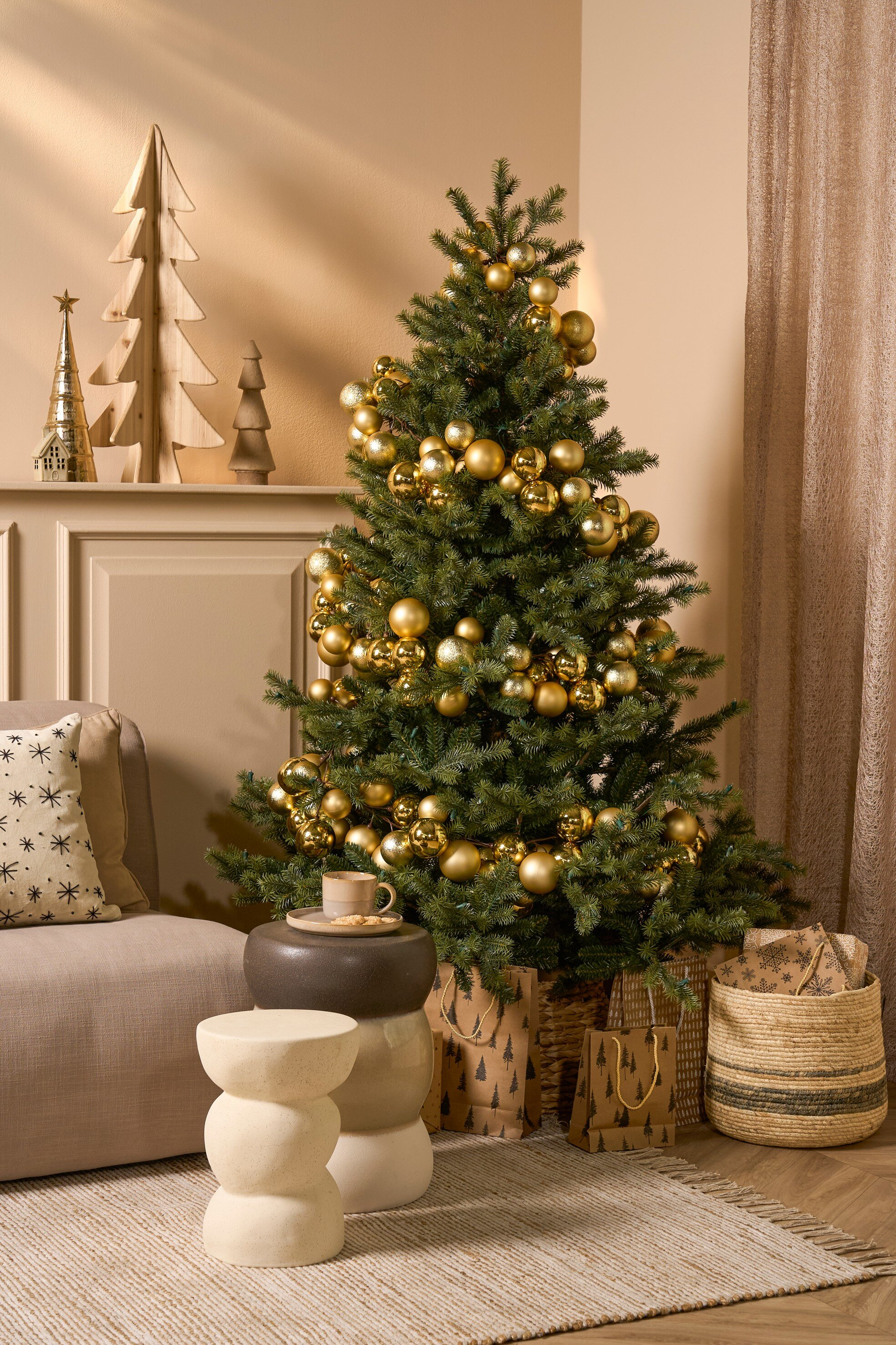 Un sapin de Noël décoré d'ornements dorés, de cadeaux et d'un cadre de salon cosy.