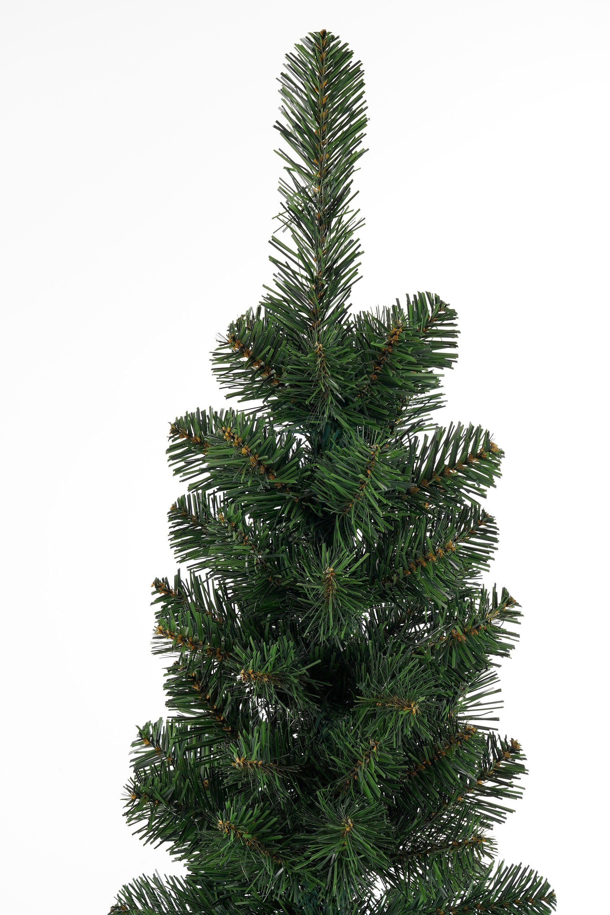 Gros plan sur un sapin de Noël artificiel vert sur fond blanc.