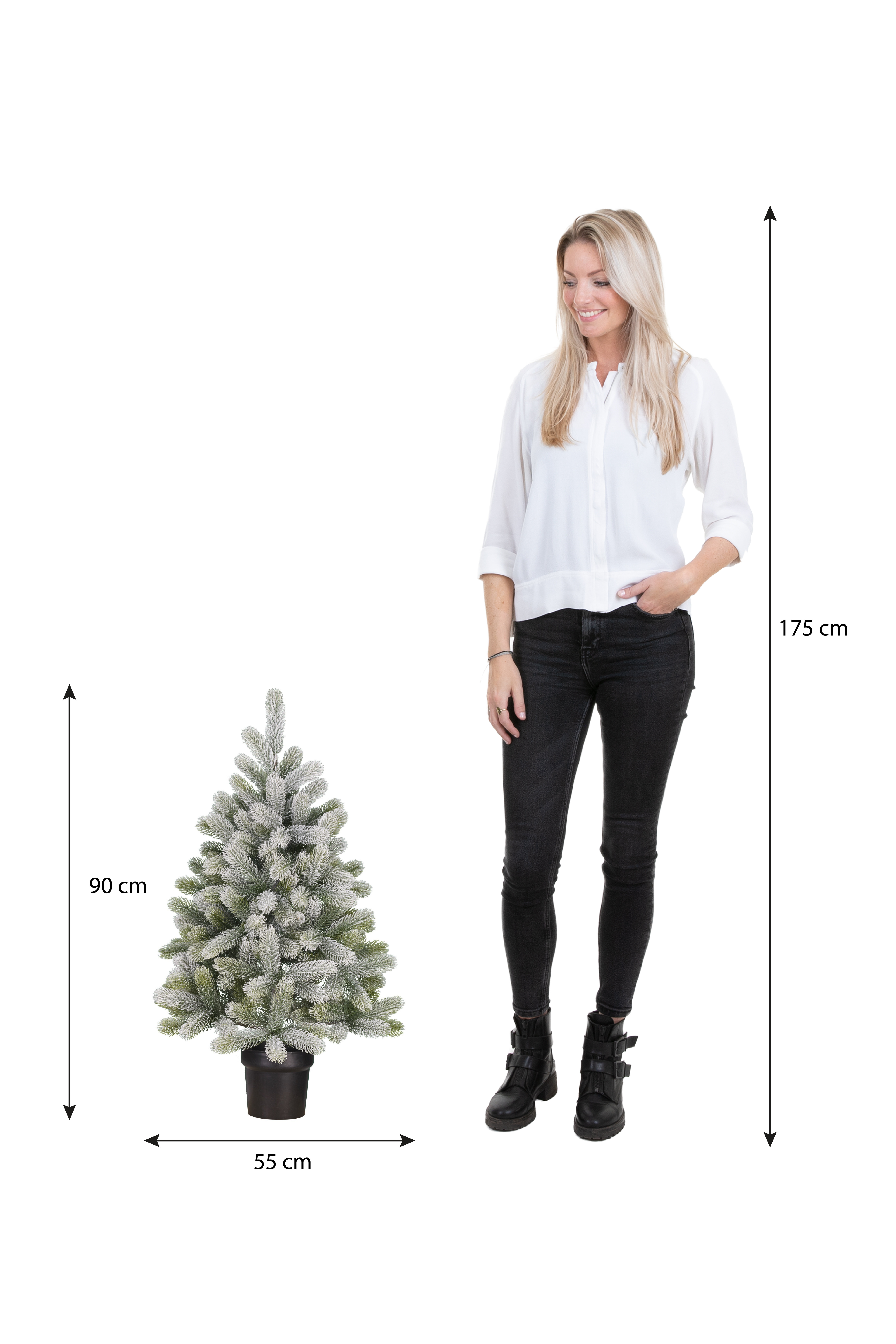 Une femme se tient près d'un petit arbre de Noël. L'arbre est dans un pot. La femme mesure 175 cm.