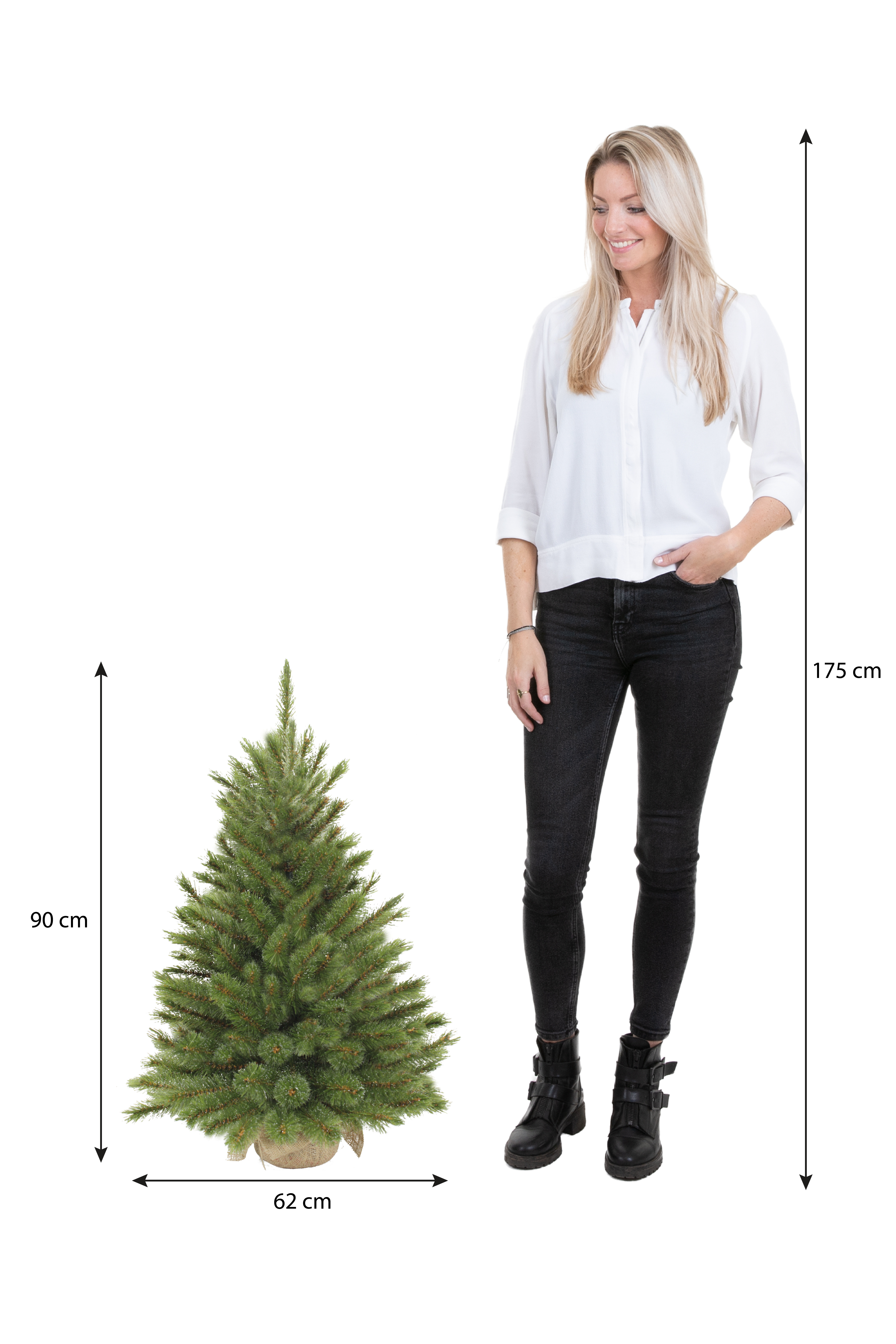 Une femme se tient à côté d'un arbre de Noël. L'arbre mesure 90 cm de haut, 62 cm de large. La femme mesure 175 cm de haut.