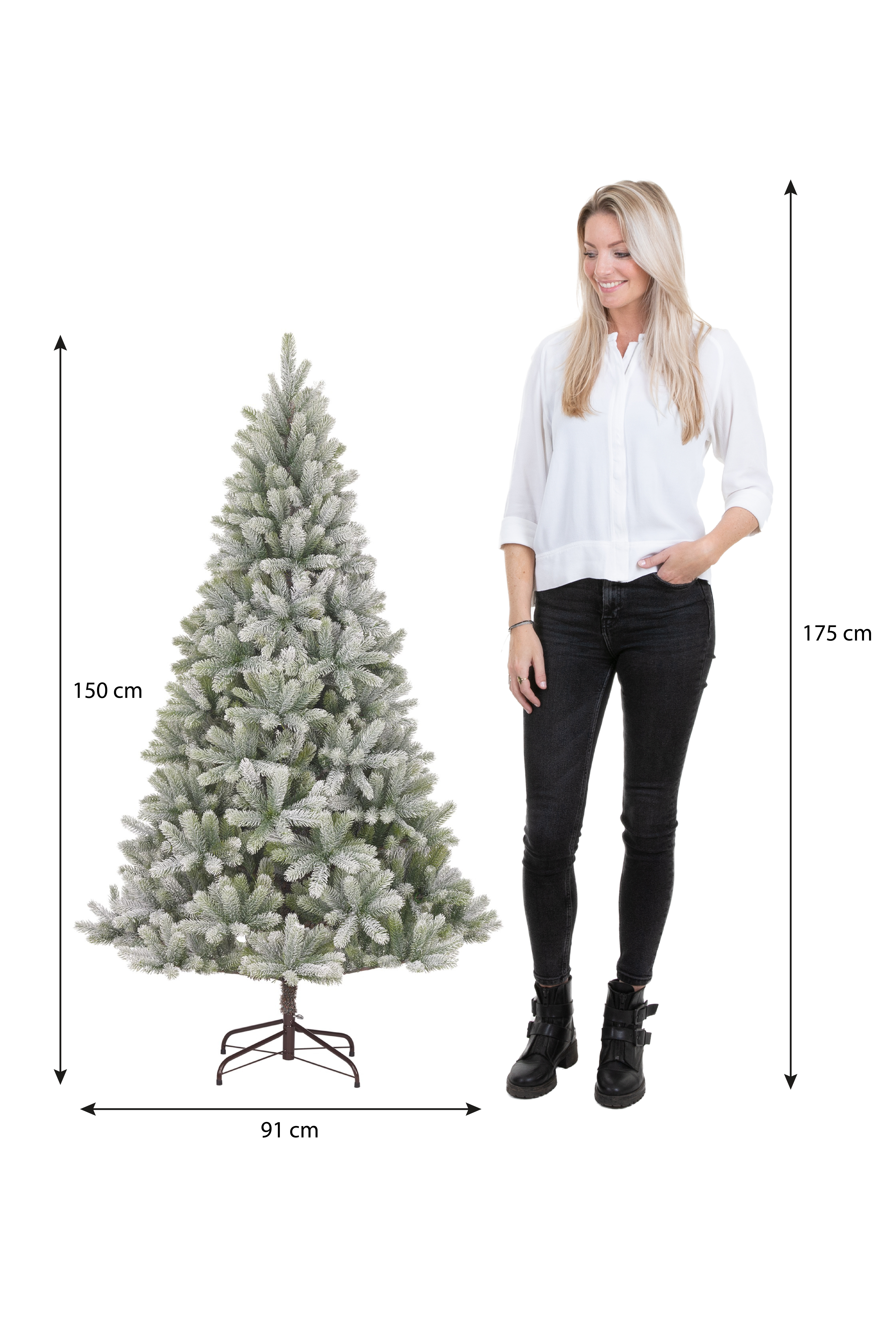 Une femme se tient à côté d'un sapin de Noël. L'arbre mesure 150 cm de haut et 91 cm de large. La femme mesure 175 cm.