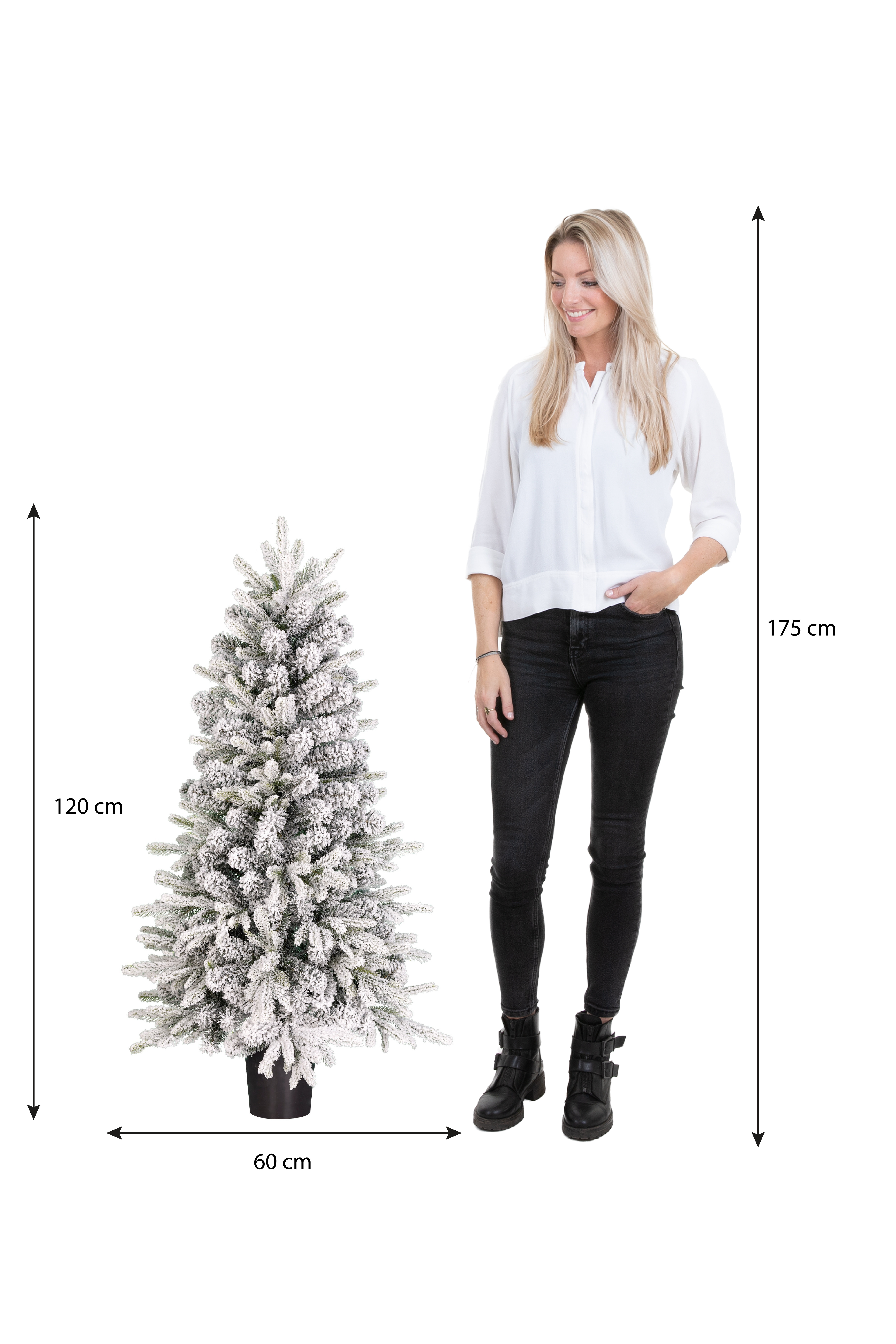 Une femme se tient à côté d'un sapin de Noël enneigé. Des mesures sont affichées. La femme porte un pantalon et des bottes noirs.