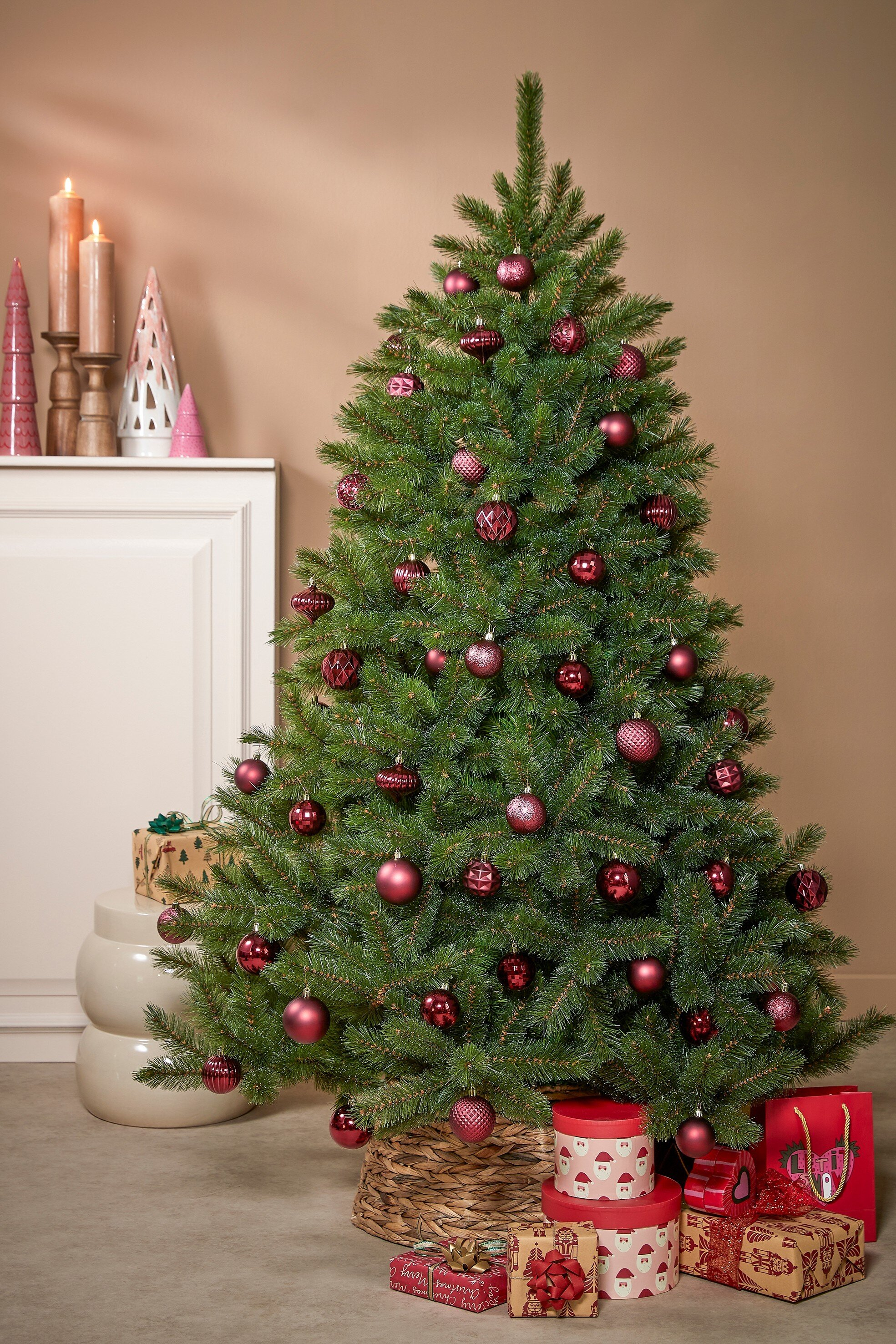 Un sapin de Noël décoré avec des ornements rouges et des cadeaux en dessous. Bougies et décorations en arrière-plan.