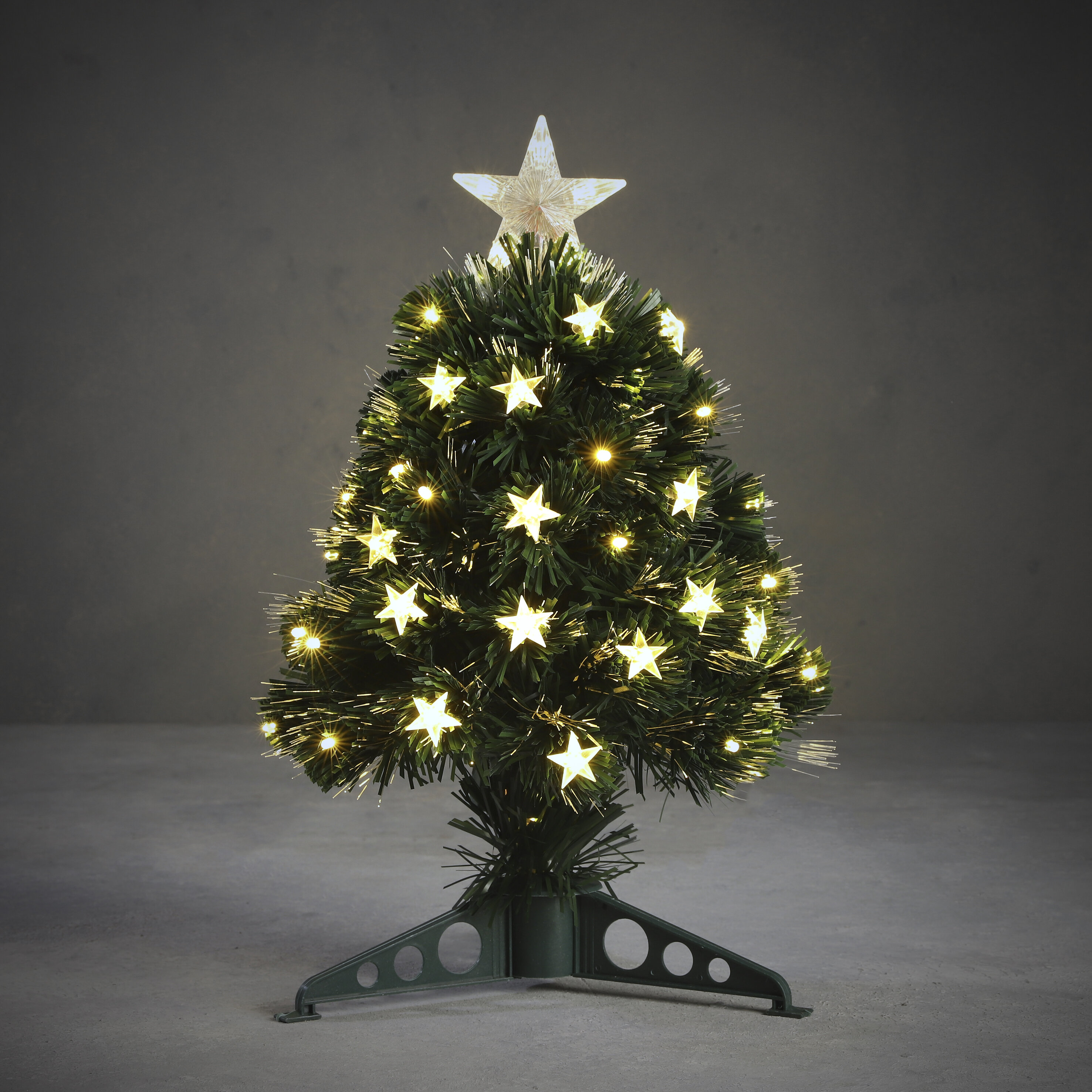 Un petit sapin de Noël avec des lumières en forme d'étoile et une étoile au sommet, sur une base verte.