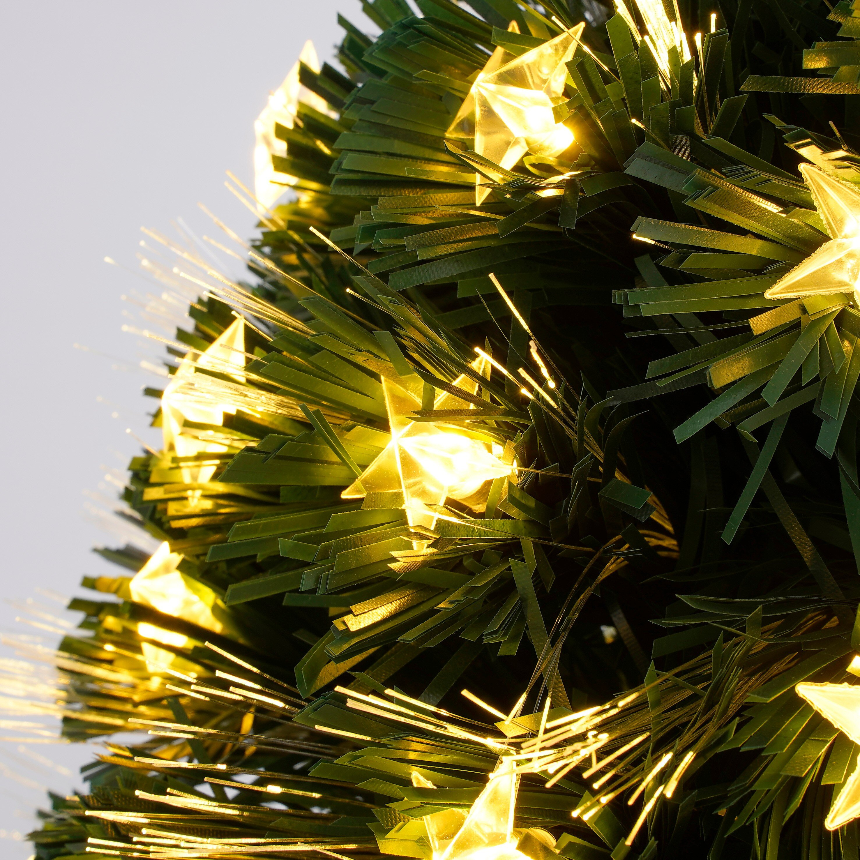Gros plan sur un sapin de Noël avec des lumières en forme d'étoile. L'arbre a des aiguilles vertes et les lumières sont jaunes.