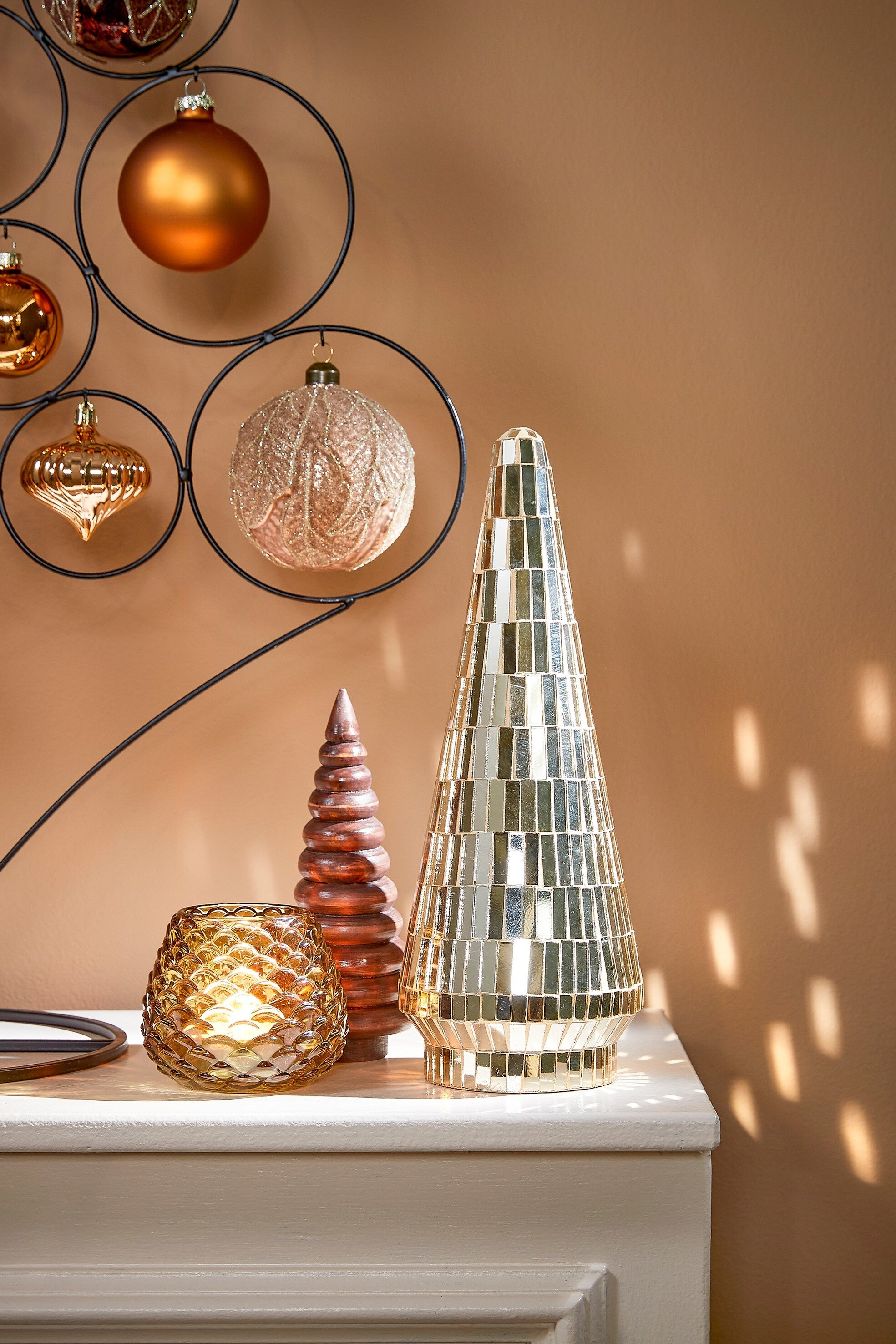 Décorations de Noël sur une surface blanche. Comprend des ornements, un bougeoir et un sapin de Noël en mosaïque.