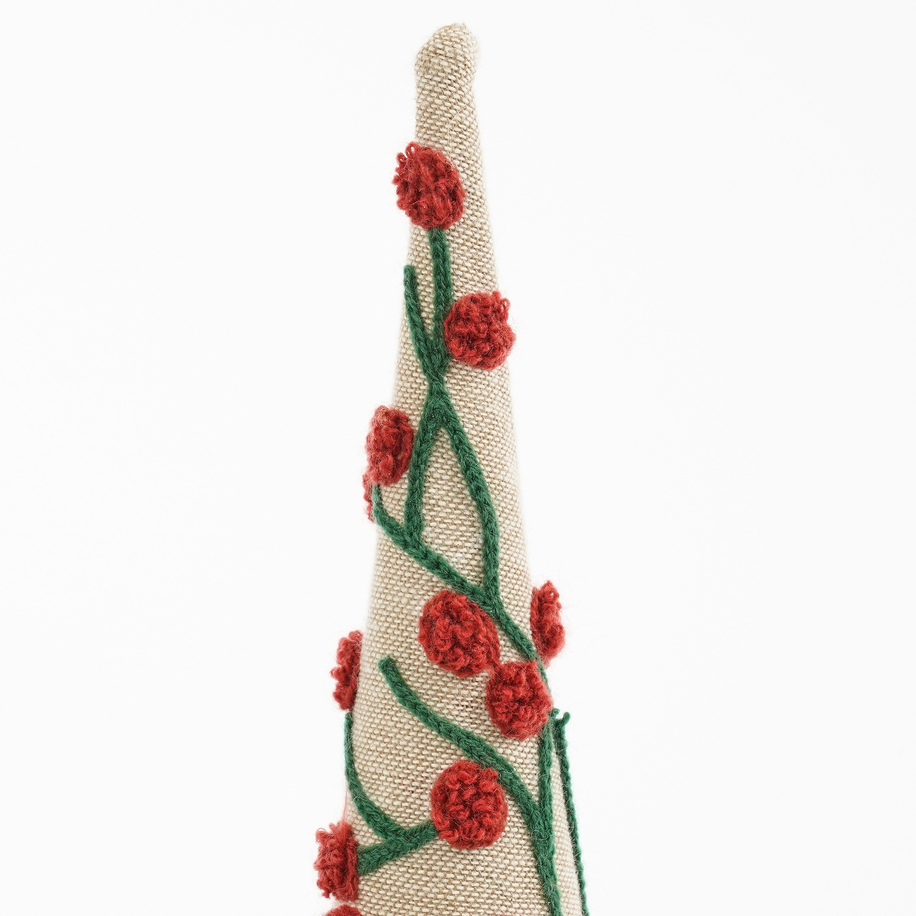 Un ornement beige en forme de cône avec broderies florales rouges et tiges vertes sur fond blanc.