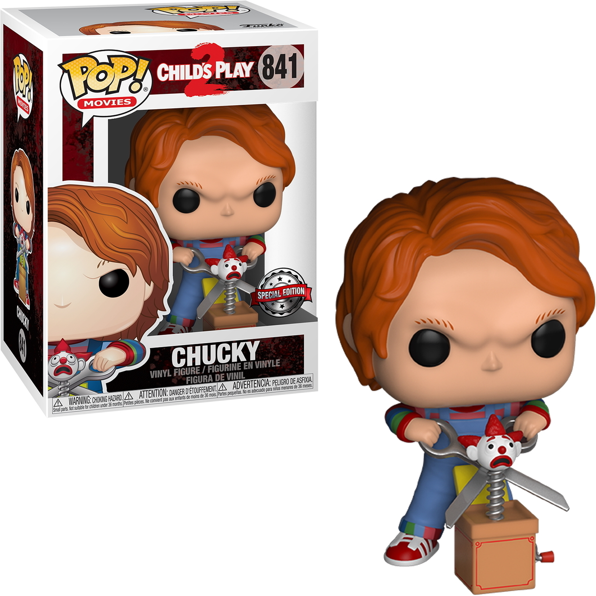 Una figura in vinile Chucky Pop! con capelli rossi, che tiene le forbici e un jack-in-the-box. Sono visibili anche una scatola e l'imballaggio.
