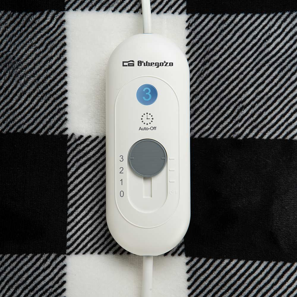 Controlador de manta eléctrica blanca sobre una manta a cuadros en blanco y negro. Números 0-3 con ajuste de apagado automático.