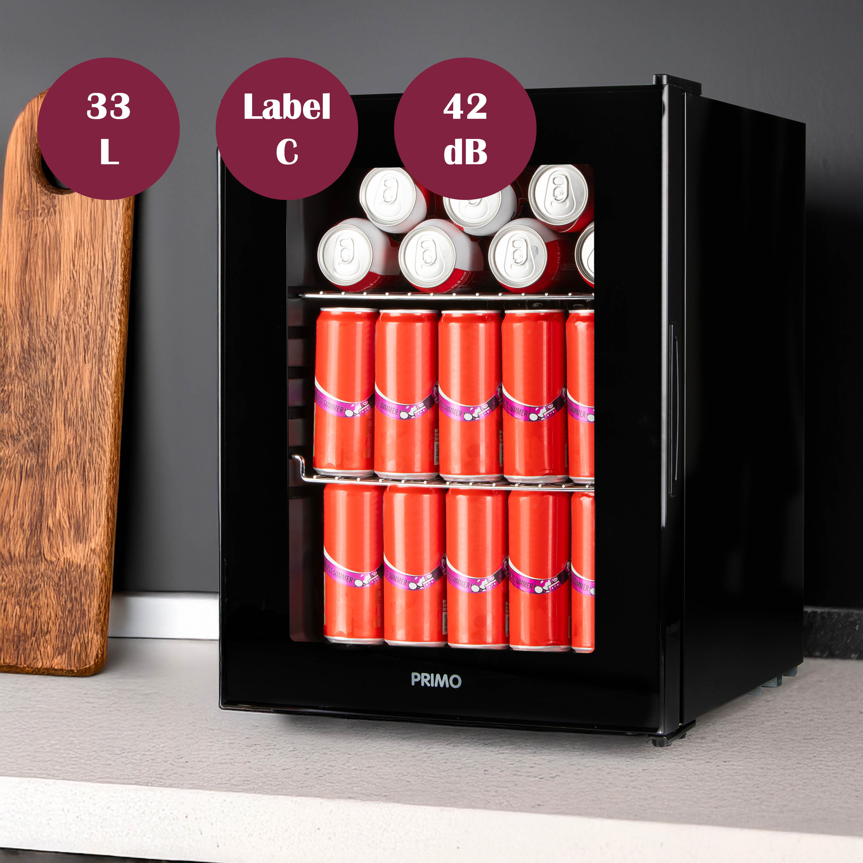 A black mini fridge with red cans inside. A wooden cutting board is to the left. Labels show 33L, C, and 42dB.