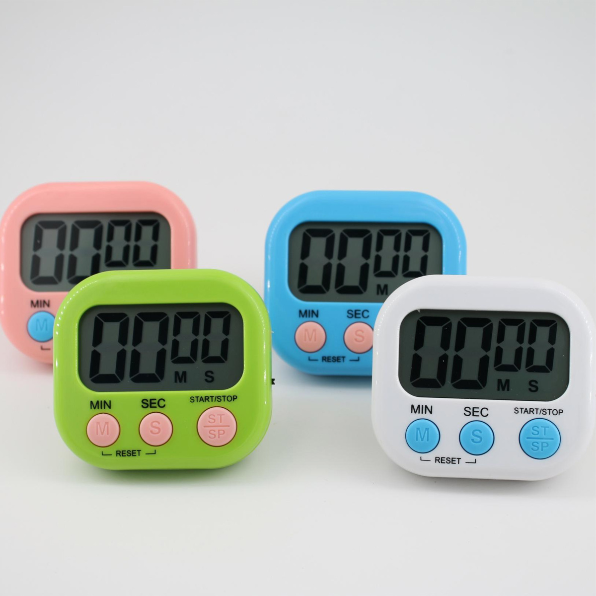 Vier digitale Küchentimer in Rosa, Grün, Blau und Weiß, die jeweils 0000 anzeigen. Tasten für Minuten, Sekunden und Start/Stopp sind sichtbar.