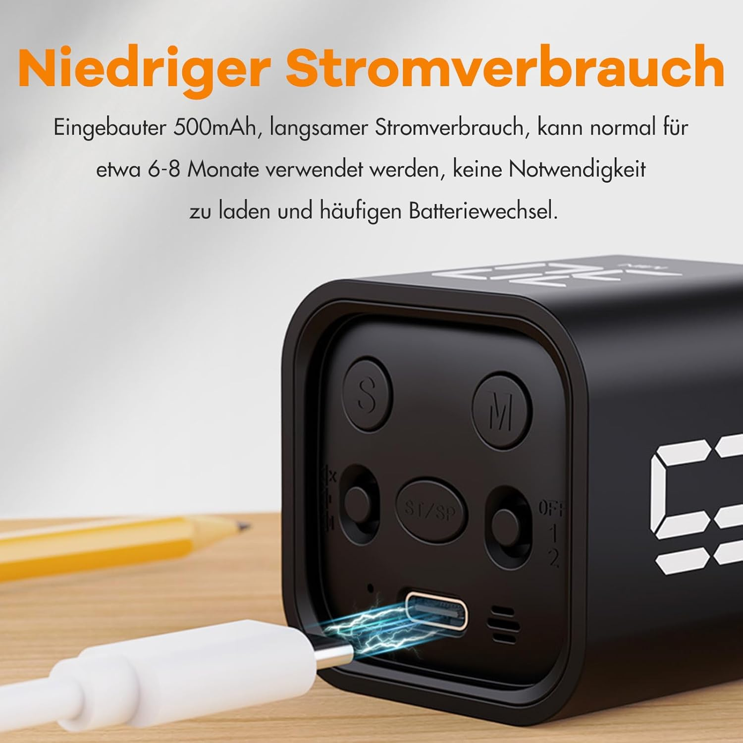 Schwarzes Gerät mit weißem Kabel, das geladen wird, und ein gelber Bleistift. Der Text lautet 'Geringer Stromverbrauch'.