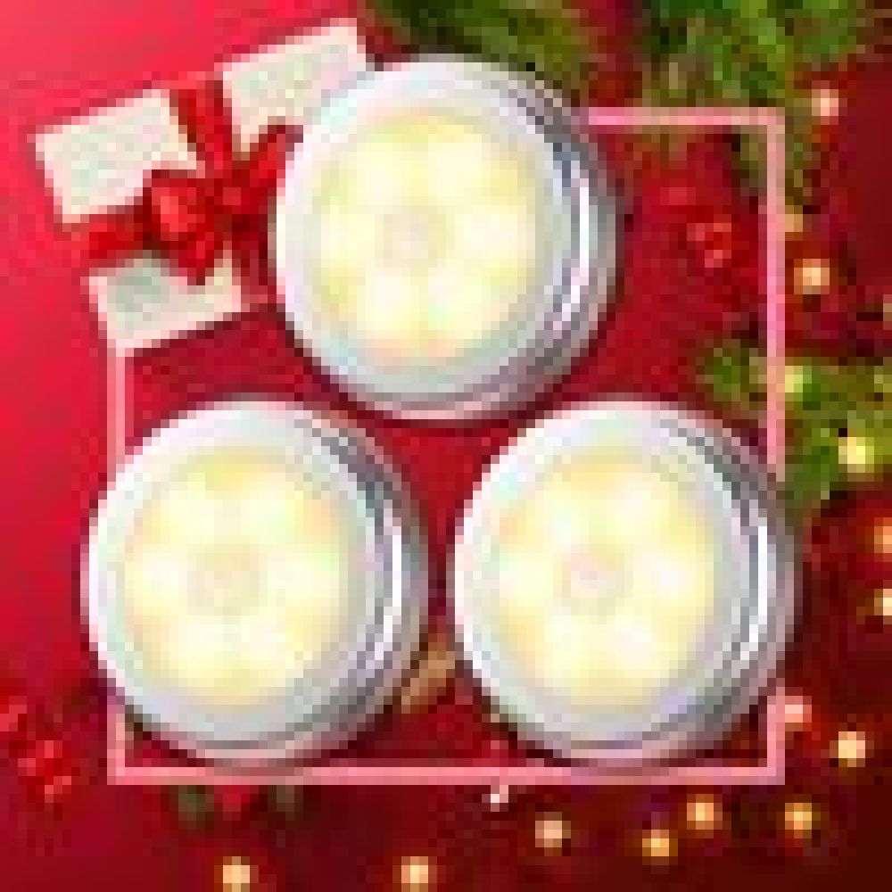 Drei runde, silbergerahmte Lichter mit sanftem Schein, angeordnet auf rotem Hintergrund. Ein Geschenk und Grünzeug akzentuieren die Szene.