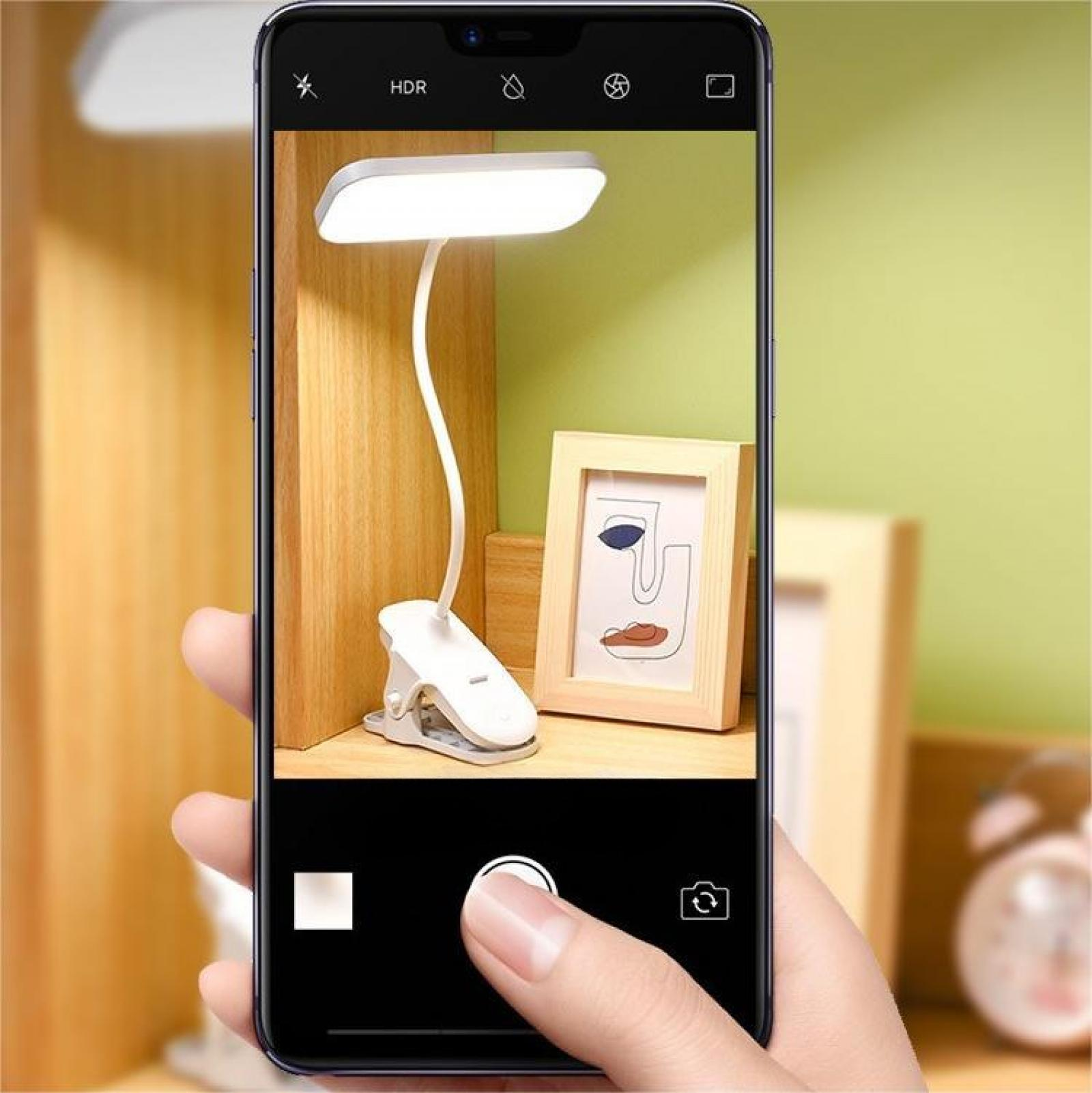 Ein Telefon nimmt eine Schreibtischlampe, einen Bilderrahmen und eine Hand auf. Der Bildschirm zeigt die Szene.