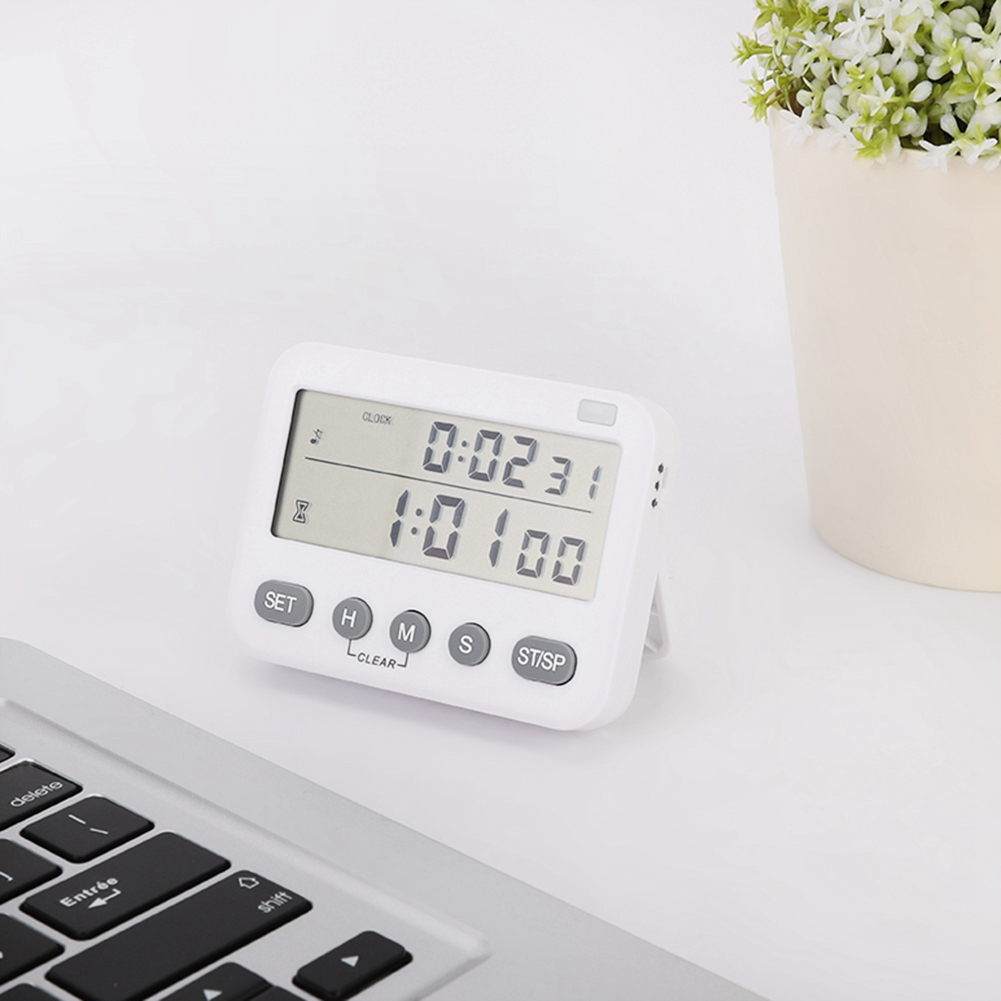 Ein weißer digitaler Timer zeigt die Zeit an. Eine Tastatur und eine Pflanze in einem beigen Topf sind ebenfalls zu sehen.