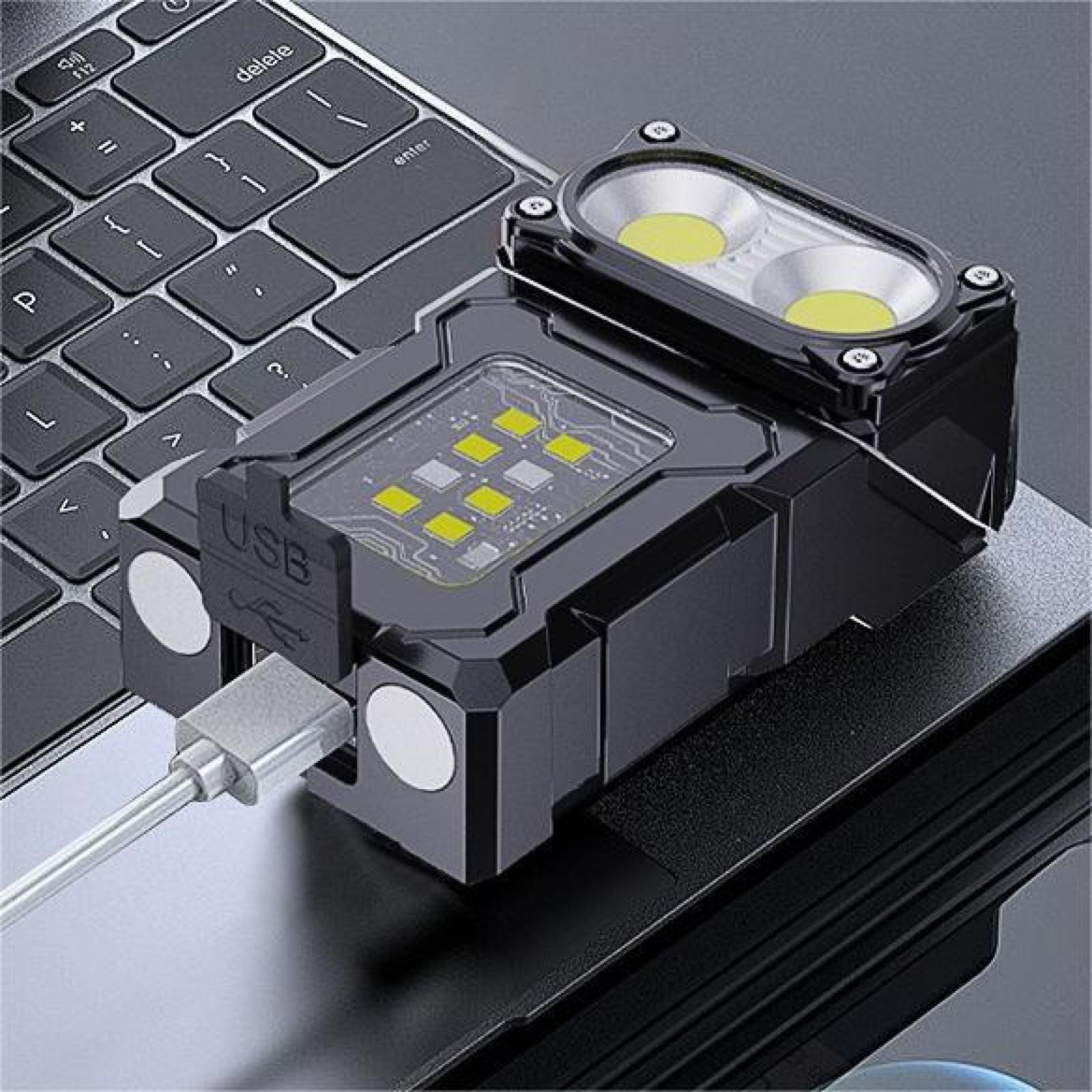 Schwarze LED-Taschenlampe auf einer Laptop-Tastatur. Sie hat zwei große und mehrere kleine gelbe Lichter. Ein USB-Kabel ist angeschlossen.