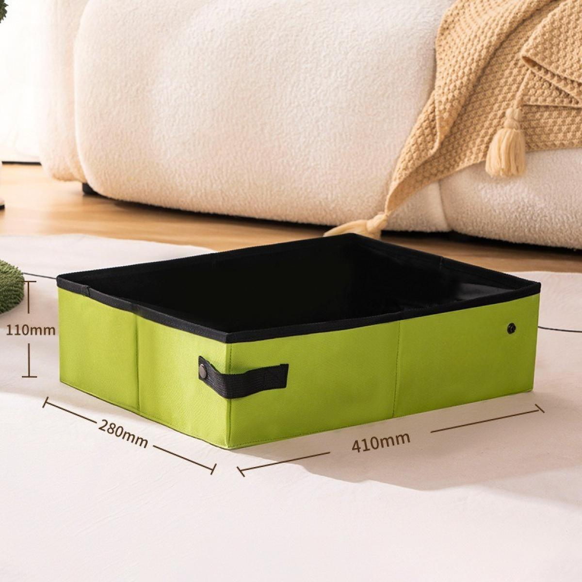 Eine grüne Aufbewahrungsbox mit schwarzem Innenraum steht auf einem weißen Teppich. Im Hintergrund sind ein weißes Sofa und eine beige Decke.