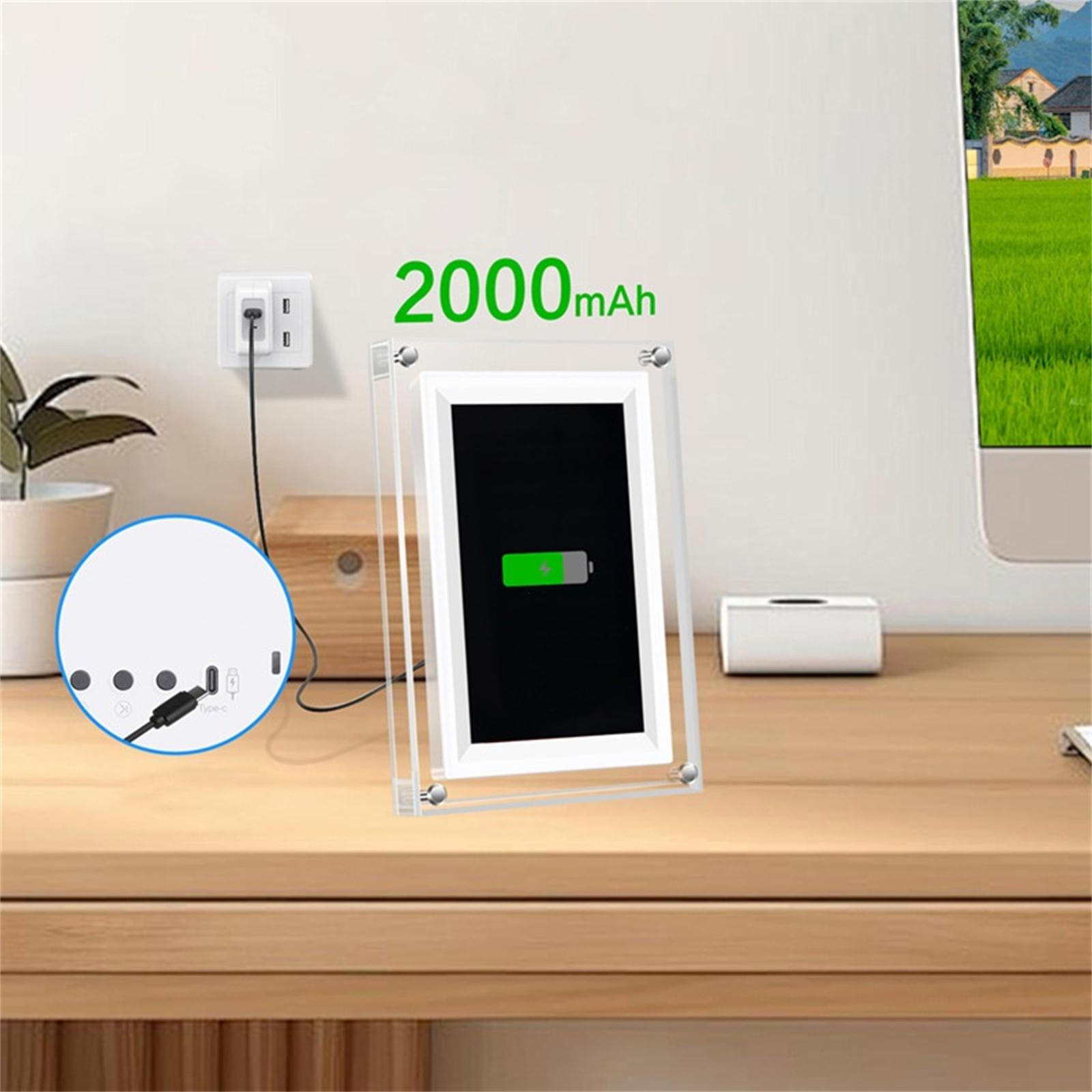Ein digitaler Bilderrahmen wird geladen. Eine Steckdose und eine Ladestation sind auf einem Holzschreibtisch sichtbar.