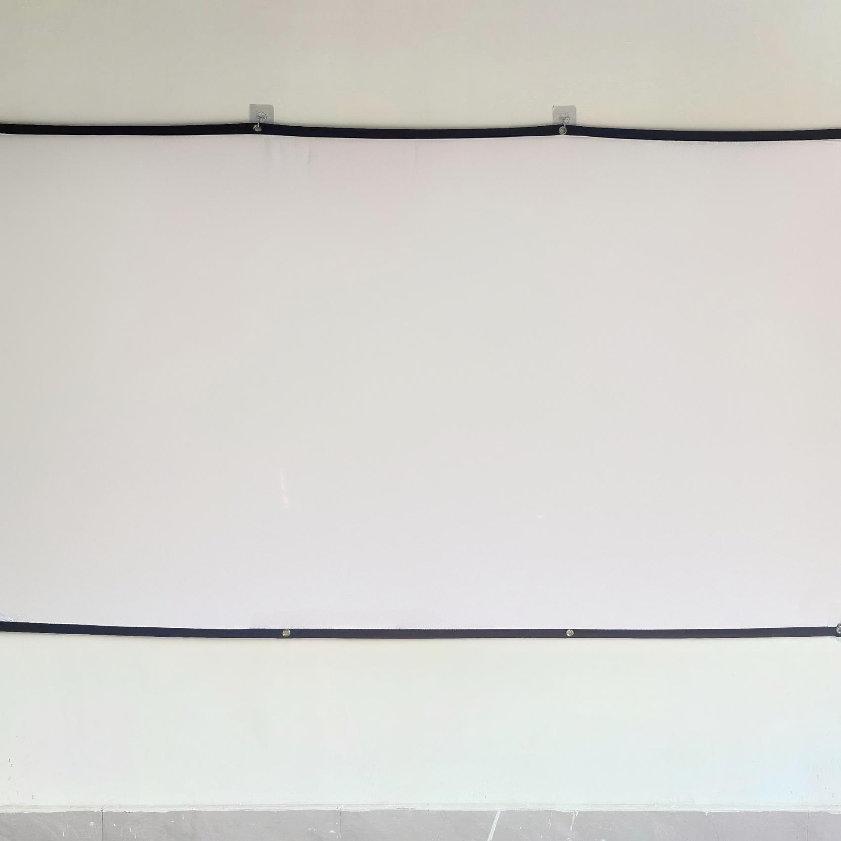 Weißer Bildschirm an einer weißen Wand mit schwarzem Rand. Haken halten den Bildschirm.