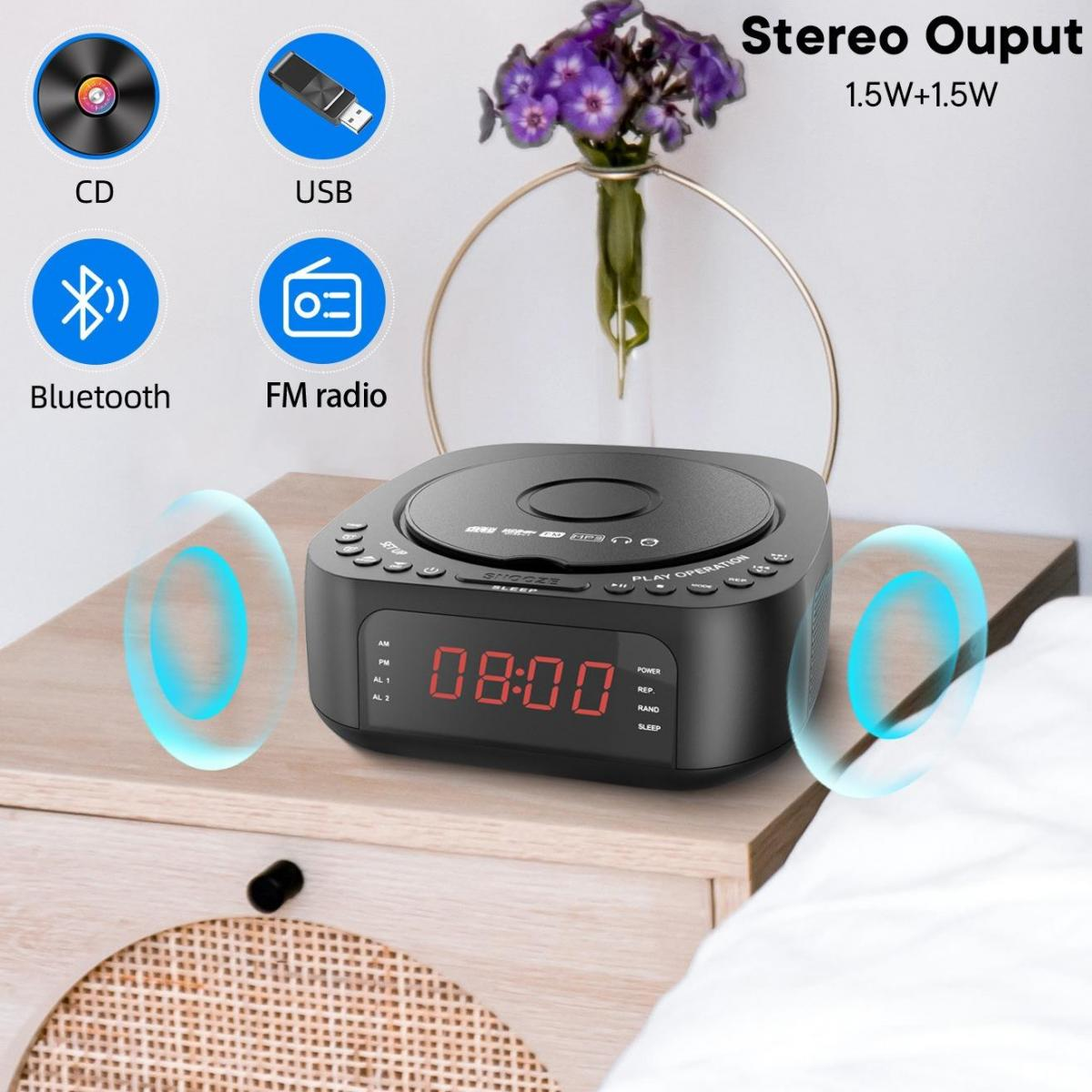 Ein schwarzes Stereo mit CD-Player, Digitaluhr und Funktionssymbolen. Lila Blumen in einer Vase auf einem Nachttisch aus Holz mit einem weißen Bett.