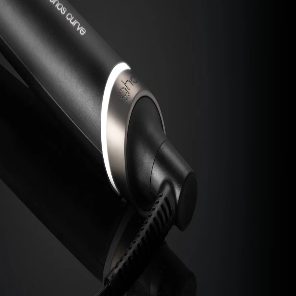 Nahaufnahme eines schwarzen Lockenstabs mit silbernem Band und weißem Licht. Das Kabel ist sichtbar, mit einer reflektierenden schwarzen Oberfläche.