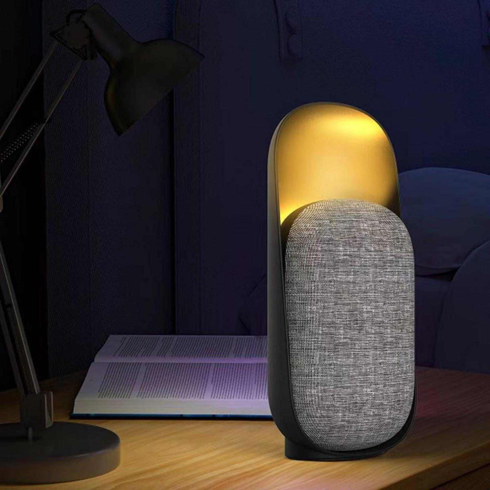 Nachttischszene mit Lampe und Lautsprecher. Ein Buch ist auf dem Tisch geöffnet. Die Beleuchtung ist sanft und warm.