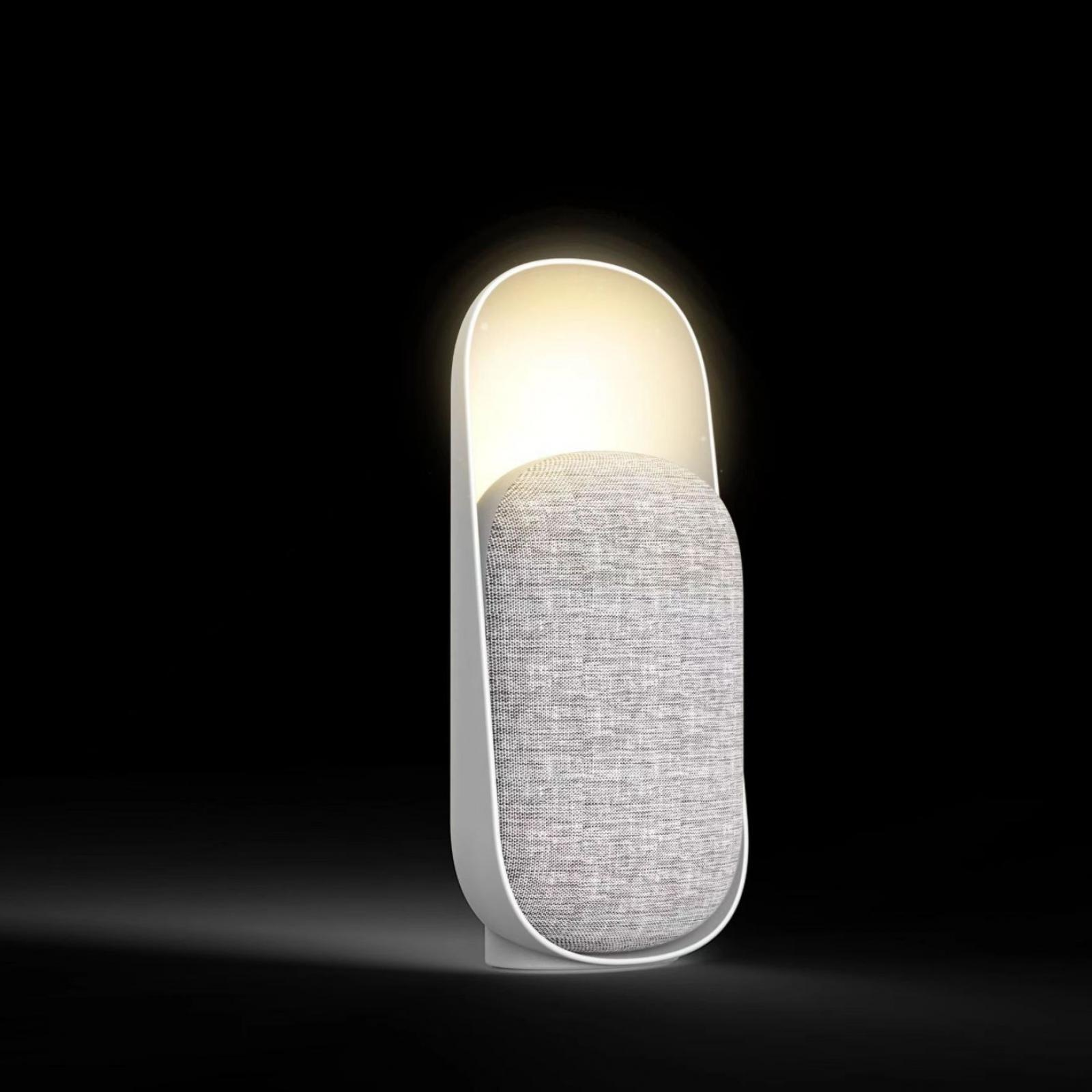 Eine moderne Lampe mit weißem Rahmen und grauem, Lautsprecher-ähnlichem Zentrum, das weiches Licht ausstrahlt.