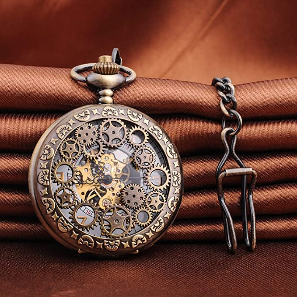 Eine bronzefarbene Taschenuhr mit sichtbaren Zahnrädern und einer Kette. Sie befindet sich vor einem braunen, strukturierten Hintergrund.
