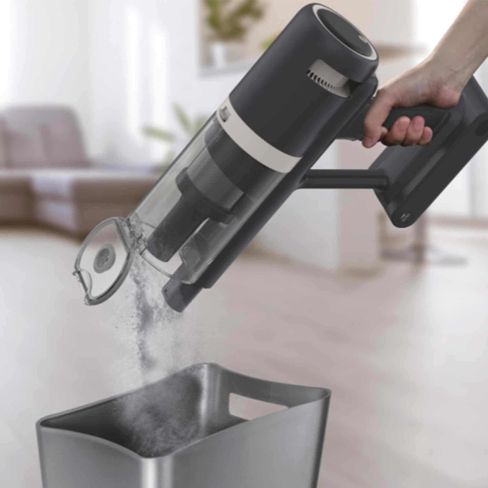 Un aspirateur à main vide la poussière dans un conteneur. L'aspirateur est noir et le conteneur est gris.