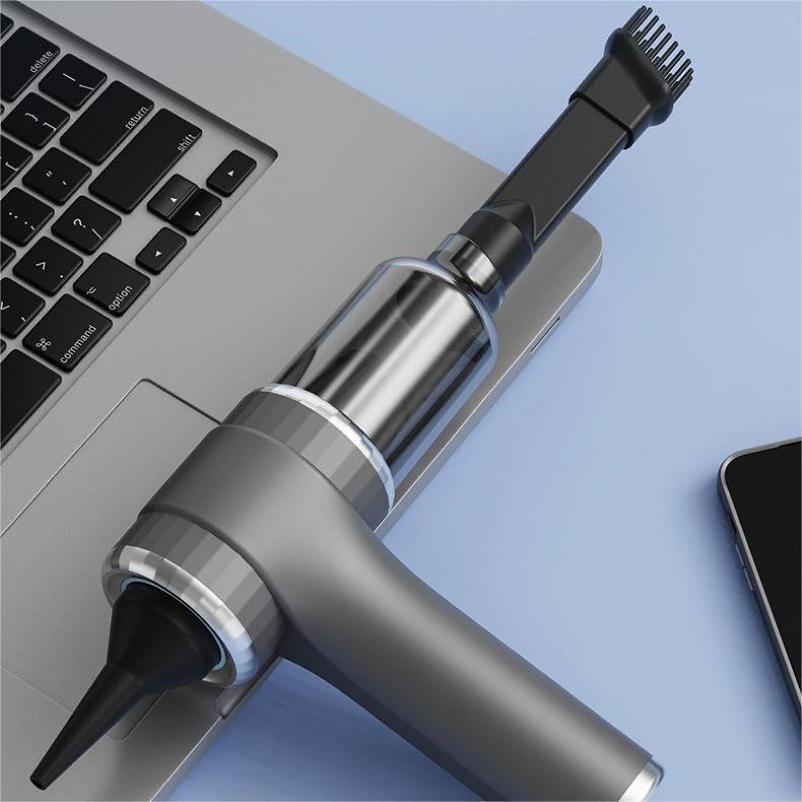 Ein Handstaubsauger auf einem Laptop. Der Staubsauger ist grau und schwarz. Ein Smartphone liegt auf einer blauen Oberfläche.