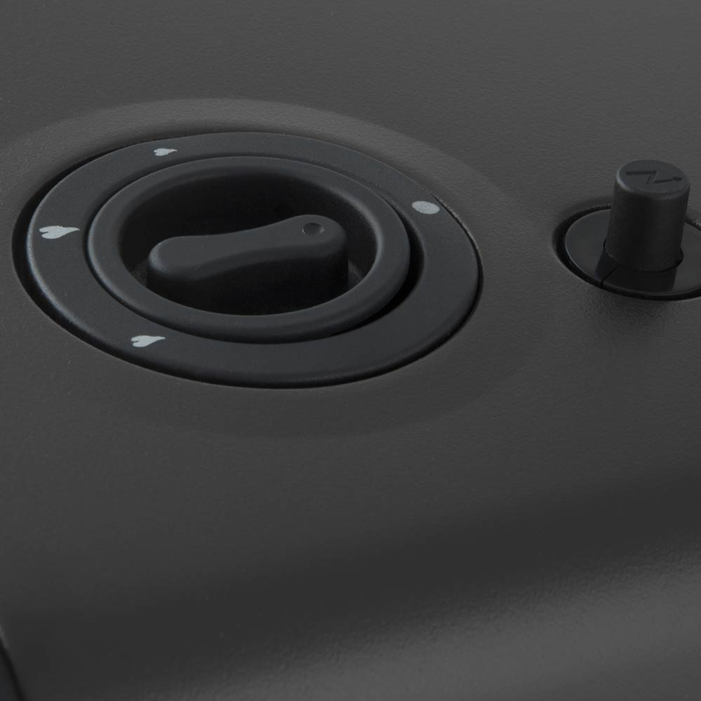 Primer plano de un panel de control negro. Tiene un dial con flechas y una perilla más pequeña. La superficie es gris oscuro.