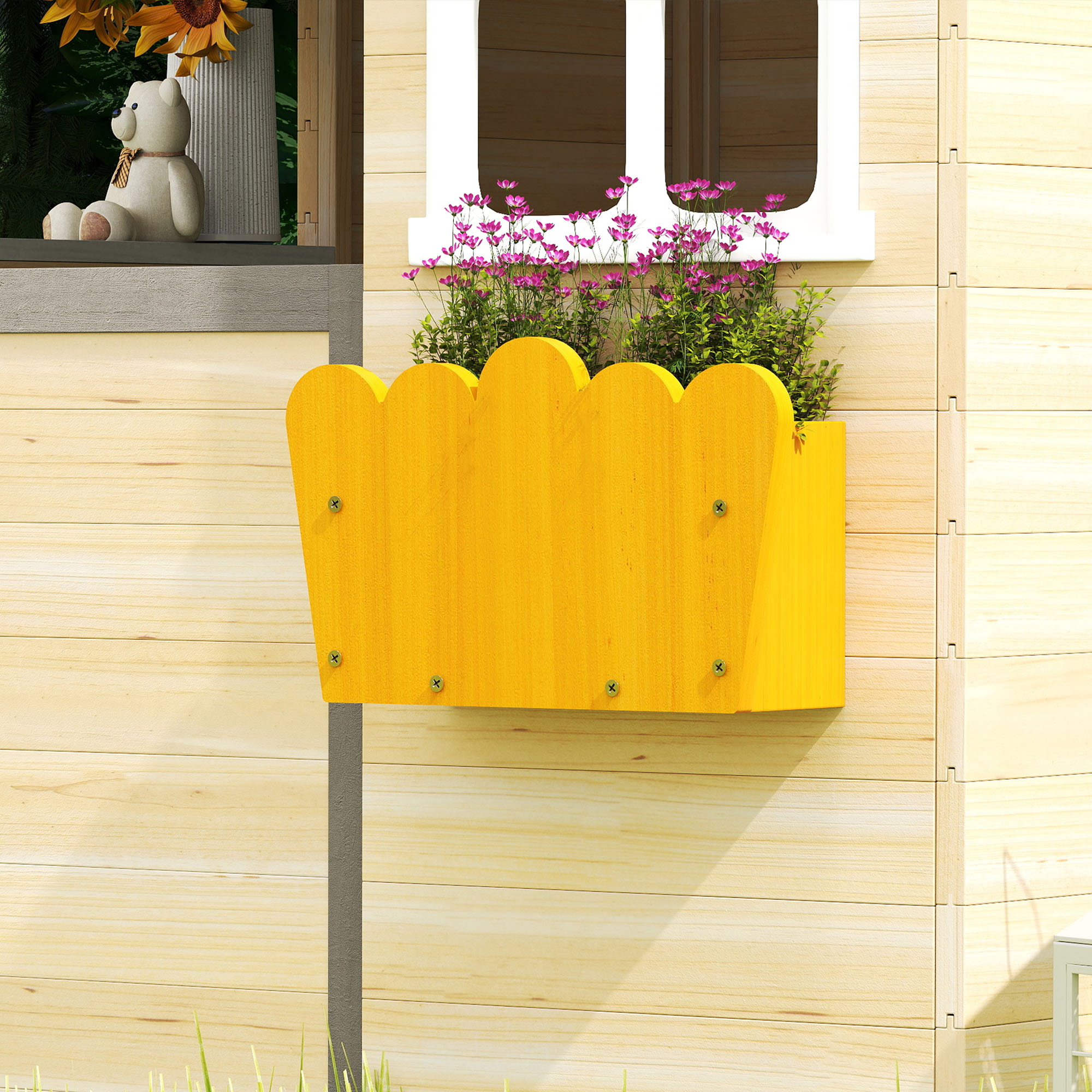 Una jardinera amarilla en una pared de madera contiene flores rosas. Una ventana muestra un oso de peluche y girasoles.
