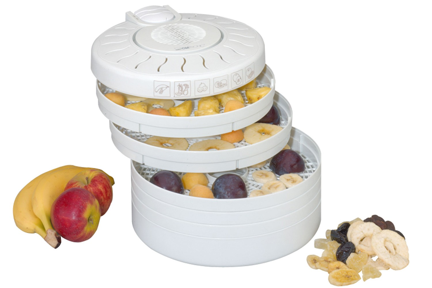 Biała suszarka do żywności z ułożonymi tacami z owocami, bananami, jabłkami i suszonymi owocami.