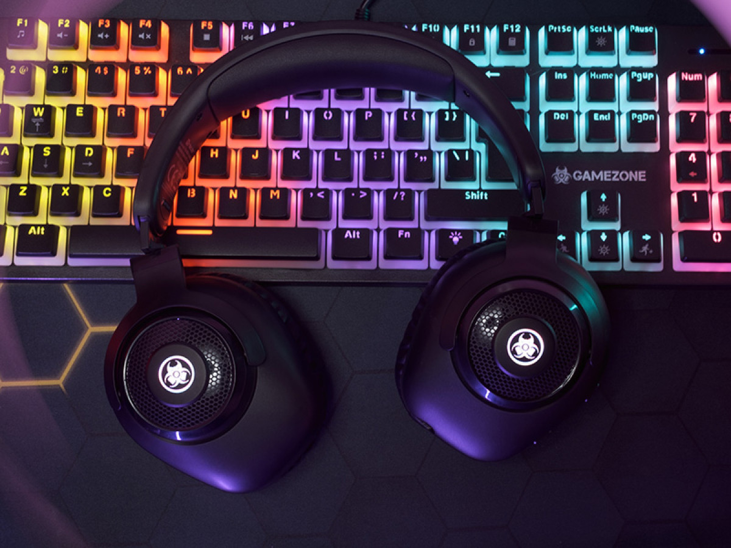 Czarne słuchawki dla graczy nad kolorową podświetlaną klawiaturą. Klawiatura wyświetla litery i cyfry.