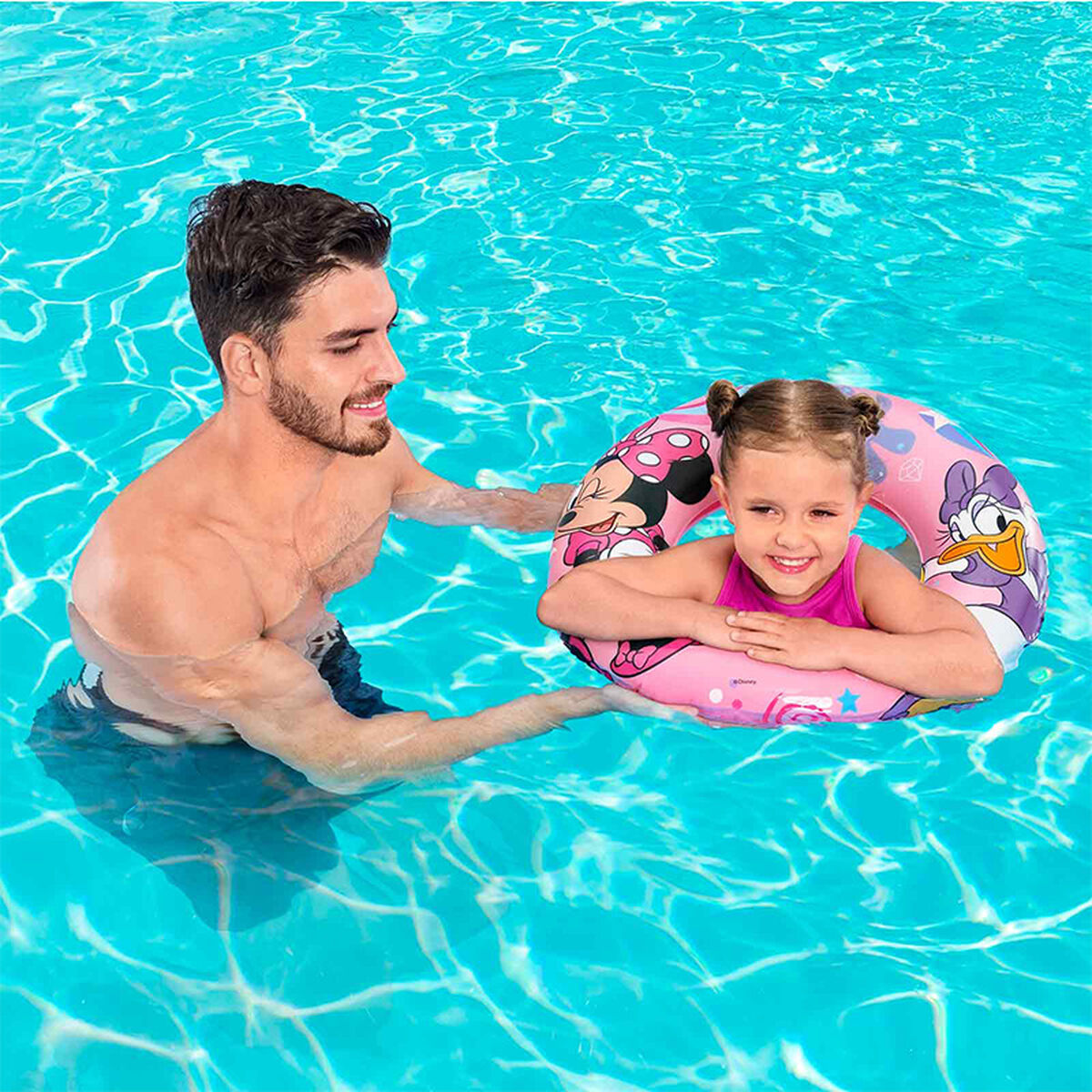 Un uomo e una ragazza in piscina. La ragazza ha un salvagente rosa. Sorridono.