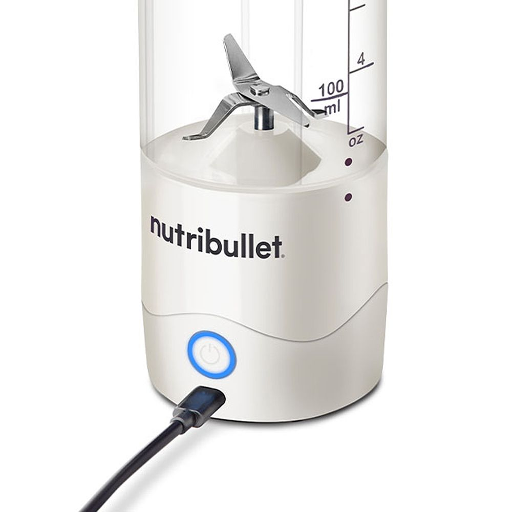 Un blender Nutribullet blanc avec un récipient transparent. Il a un bouton d'alimentation, un câble USB et un ensemble de lames.