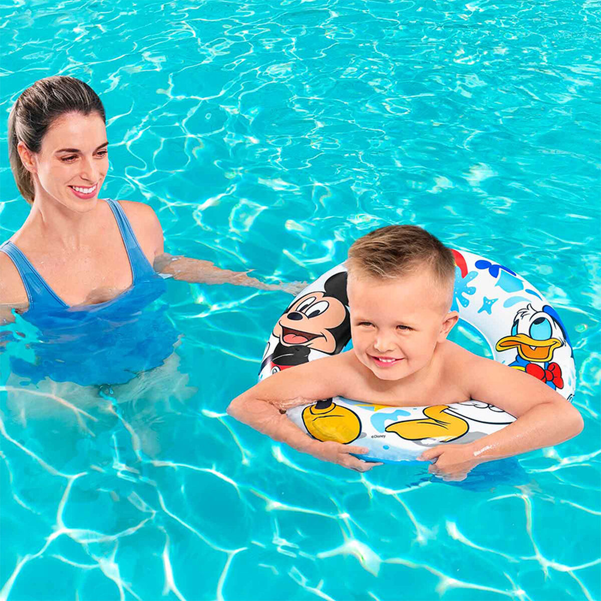 Una donna e un ragazzo in piscina. Il ragazzo è in un salvagente di Mickey Mouse. La donna indossa un costume da bagno blu.