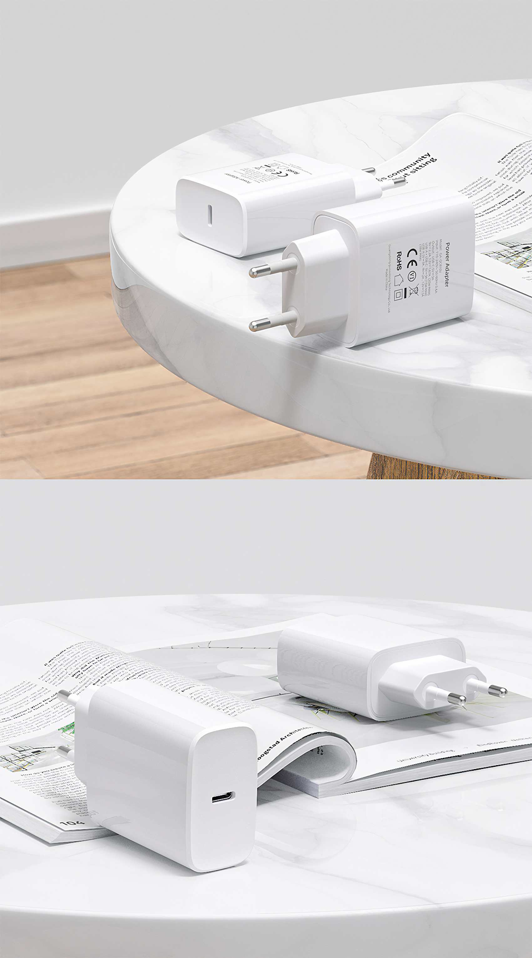 Zwei weiße Netzadapter auf einem weißen Tisch, einer mit sichtbaren Stiften. Im Hintergrund ist eine Zeitschrift teilweise sichtbar.