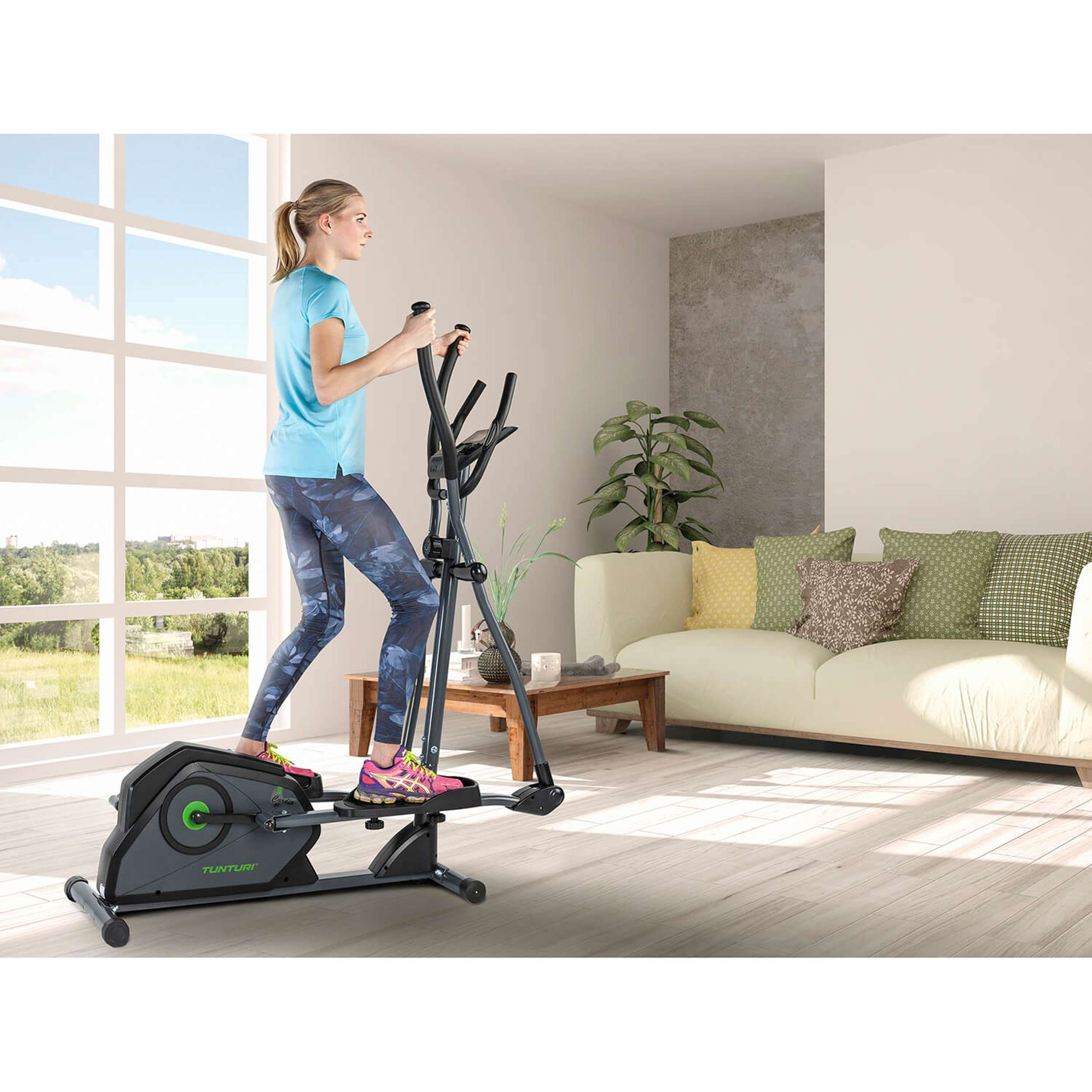 Een vrouw sport op een crosstrainer in een thuisgymnastiek. Op de achtergrond zijn een bank en een raam te zien.