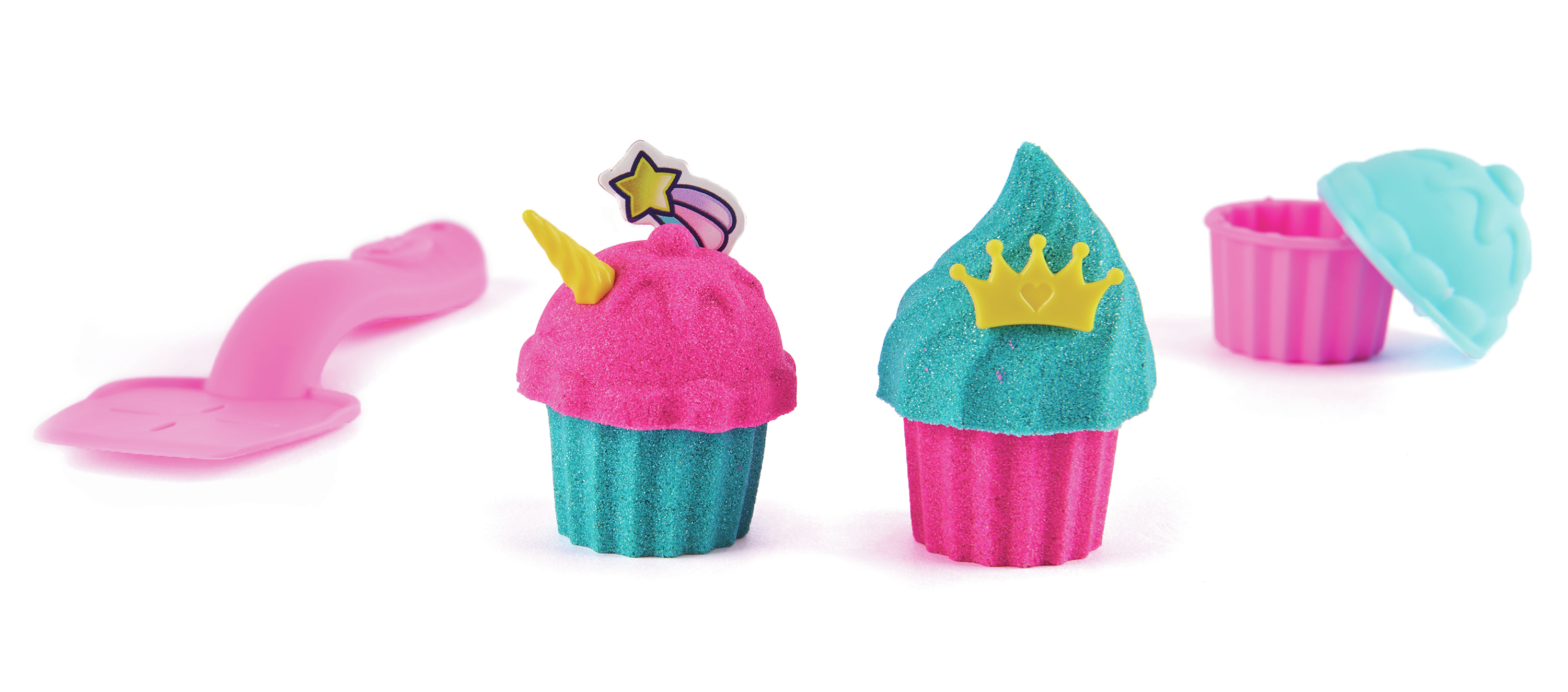 La imagen muestra cupcakes de juguete con decoraciones. Una cuchara rosa y una magdalena con cuerno de unicornio. Otra con una corona. Moldes para magdalenas.