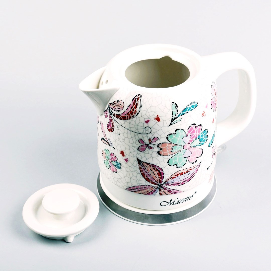 Biały czajnik elektryczny z kwiatowymi wzorami, obok pokrywka. Marka Maestro znajduje się na podstawie czajnika.