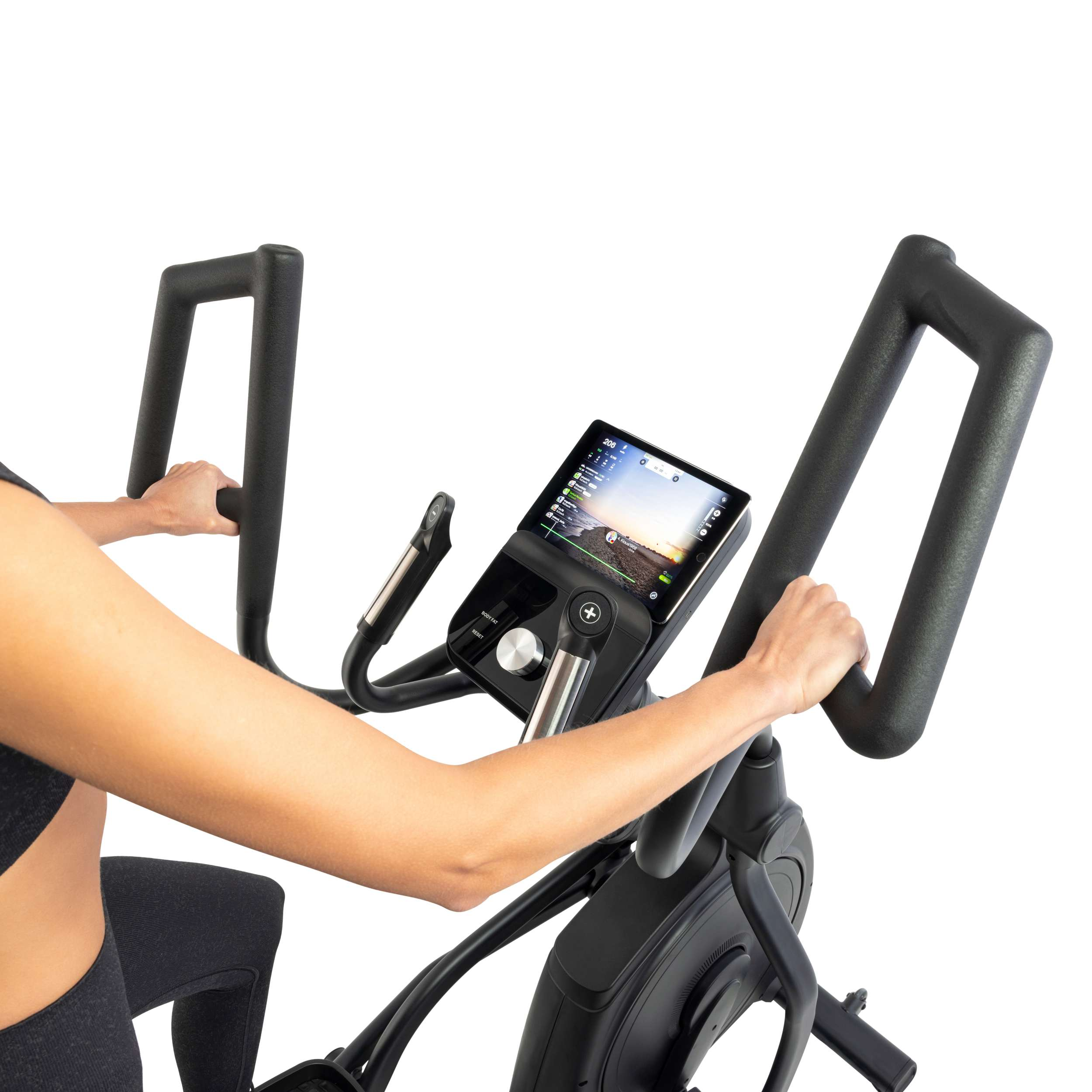 A person is using an elliptical machine. The machine has a screen displaying workout data. The person holds the handles.