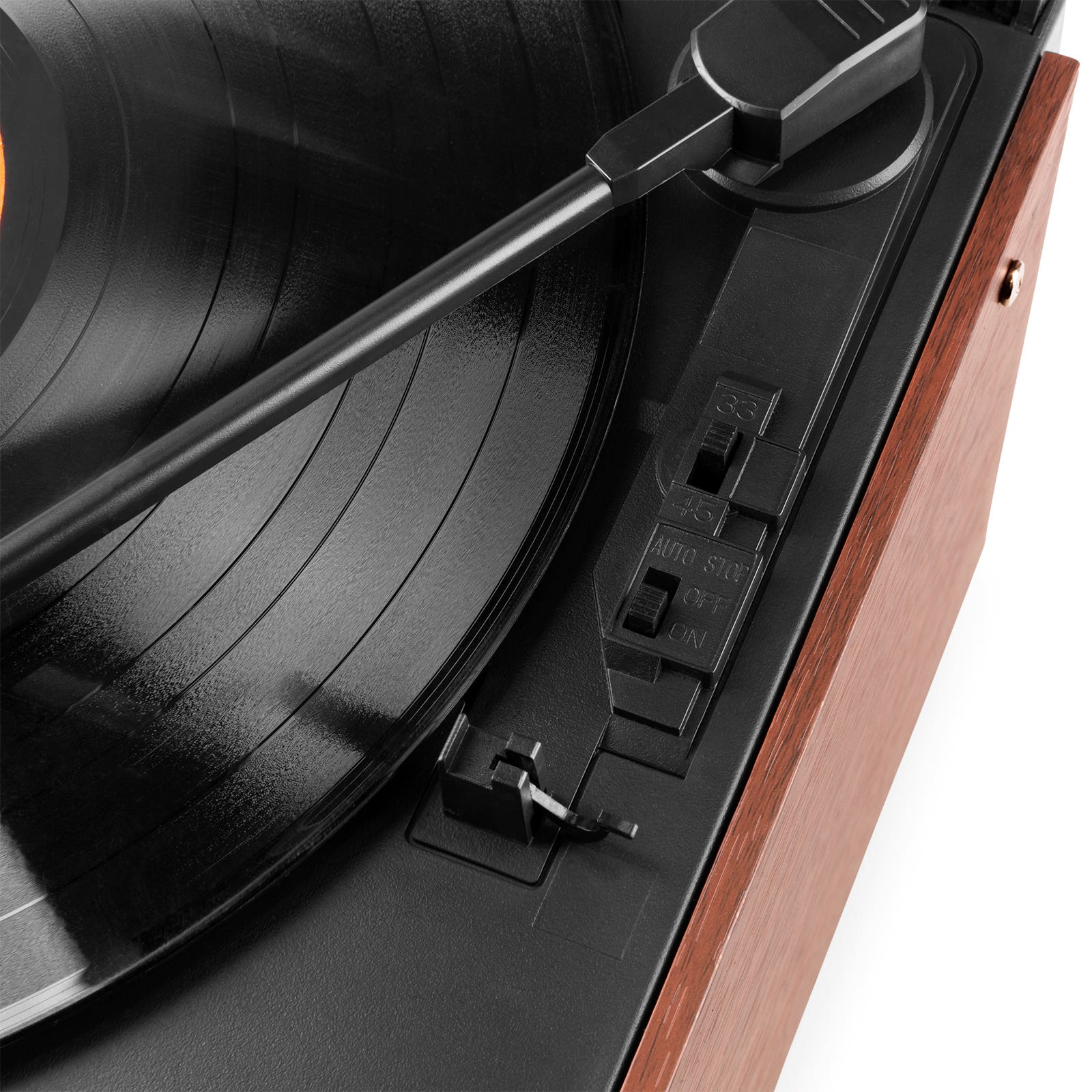 Primer plano de un tocadiscos. Un disco de vinilo negro está en el tocadiscos. El brazo del tono está sobre el disco.