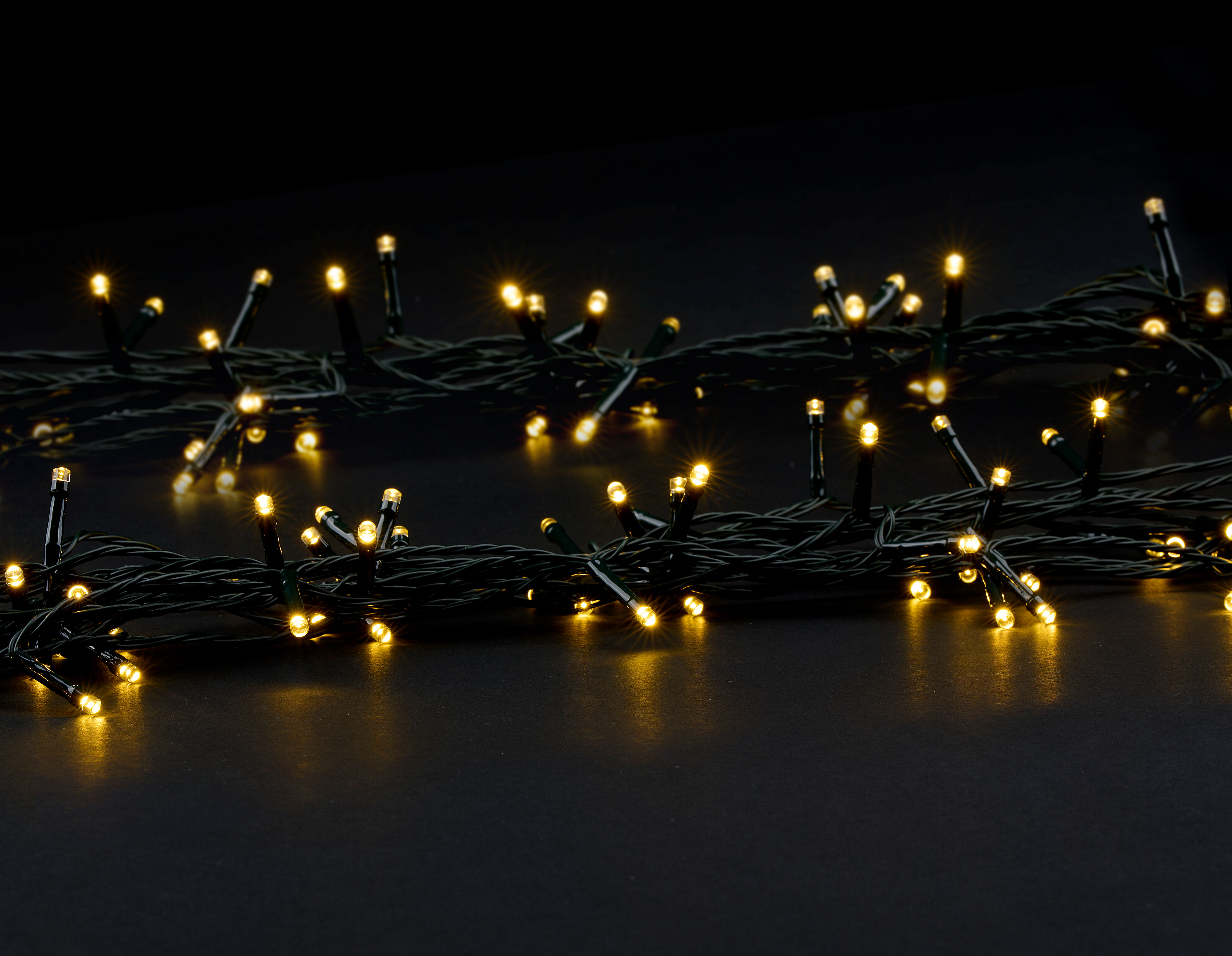 Gros plan sur une guirlande de petites lumières LED jaunes et chaudes sur fond sombre.