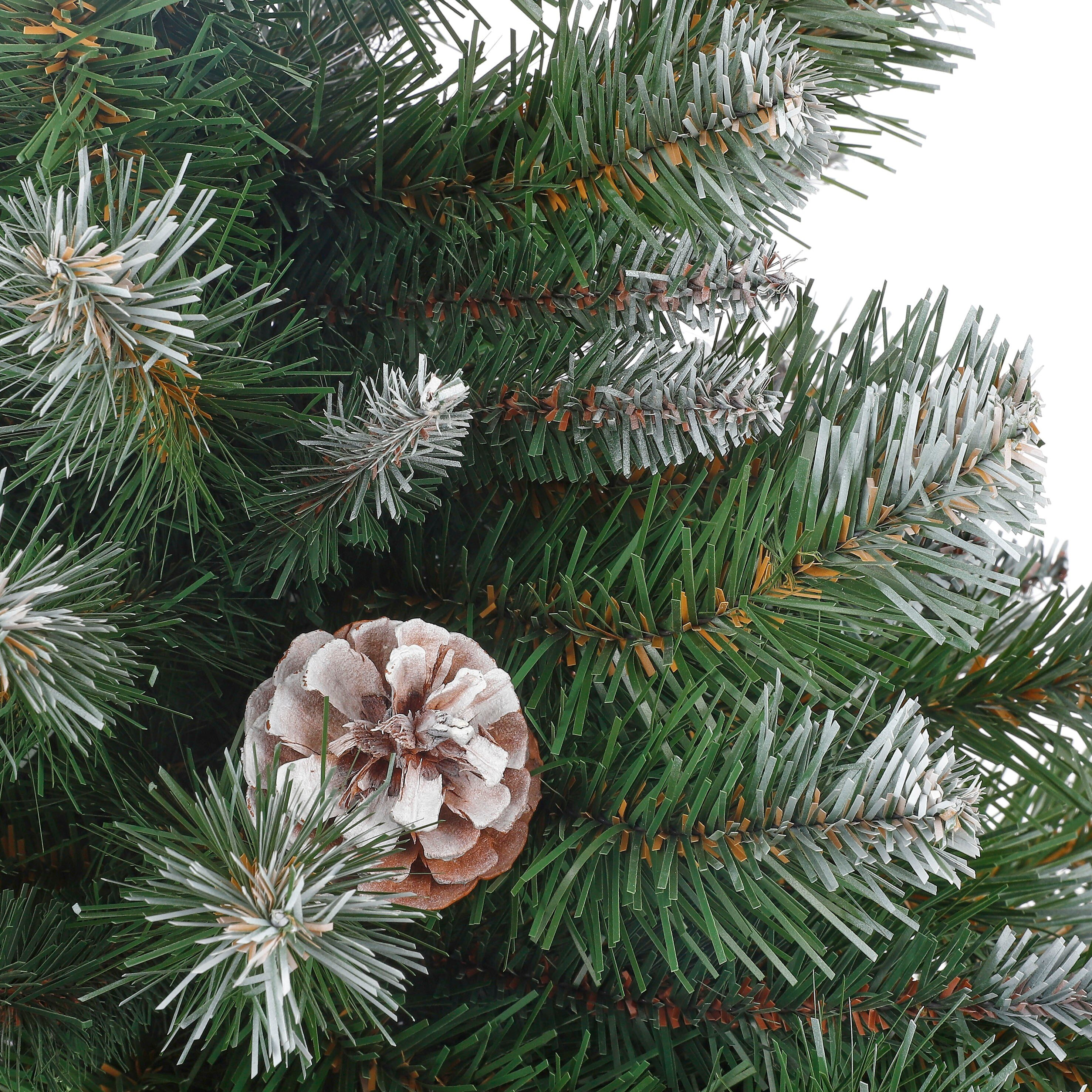 Gros plan d'une branche de sapin de Noël. Une pomme de pin est nichée parmi des aiguilles vertes givrées.
